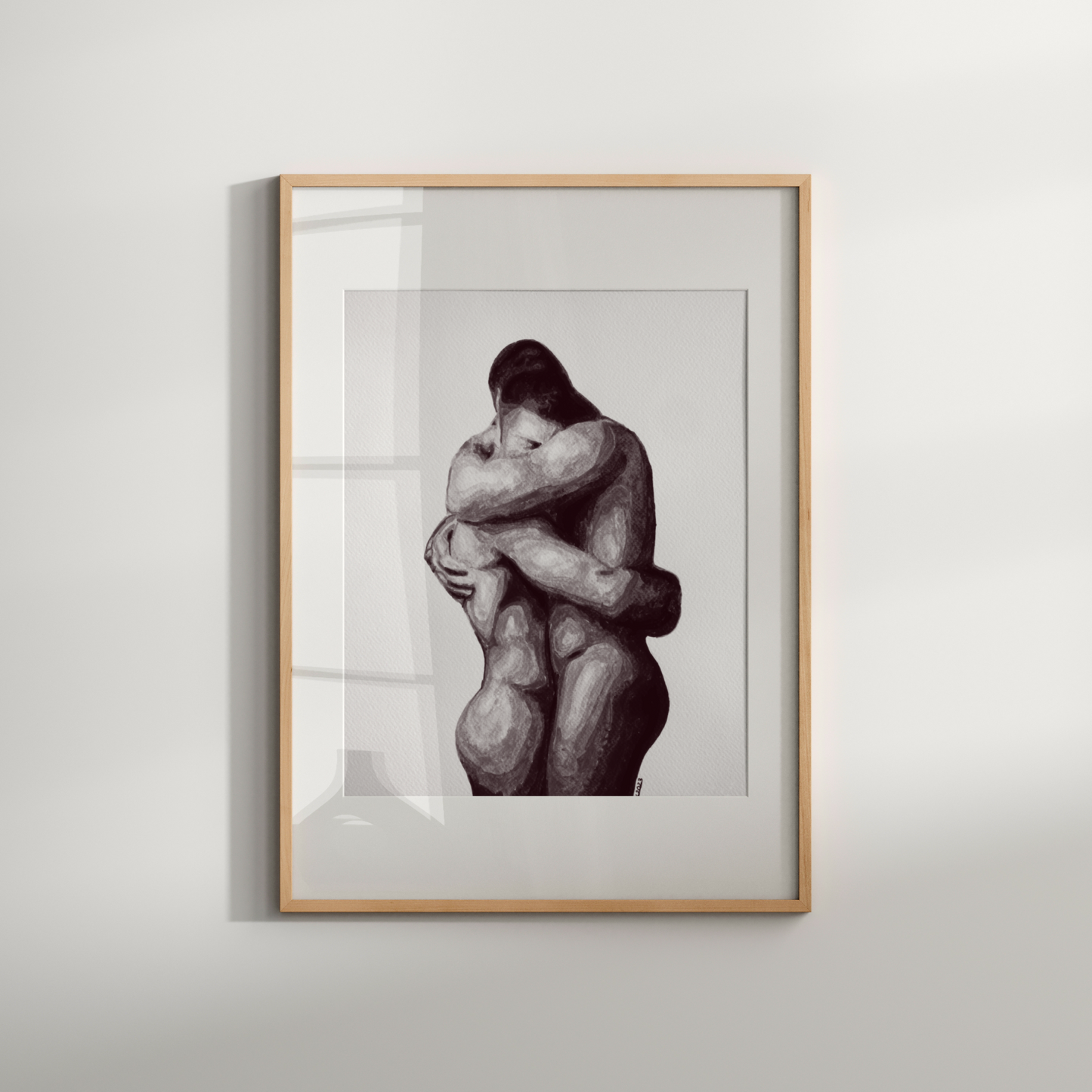 Framed artwork of two embracing figures on a white wall