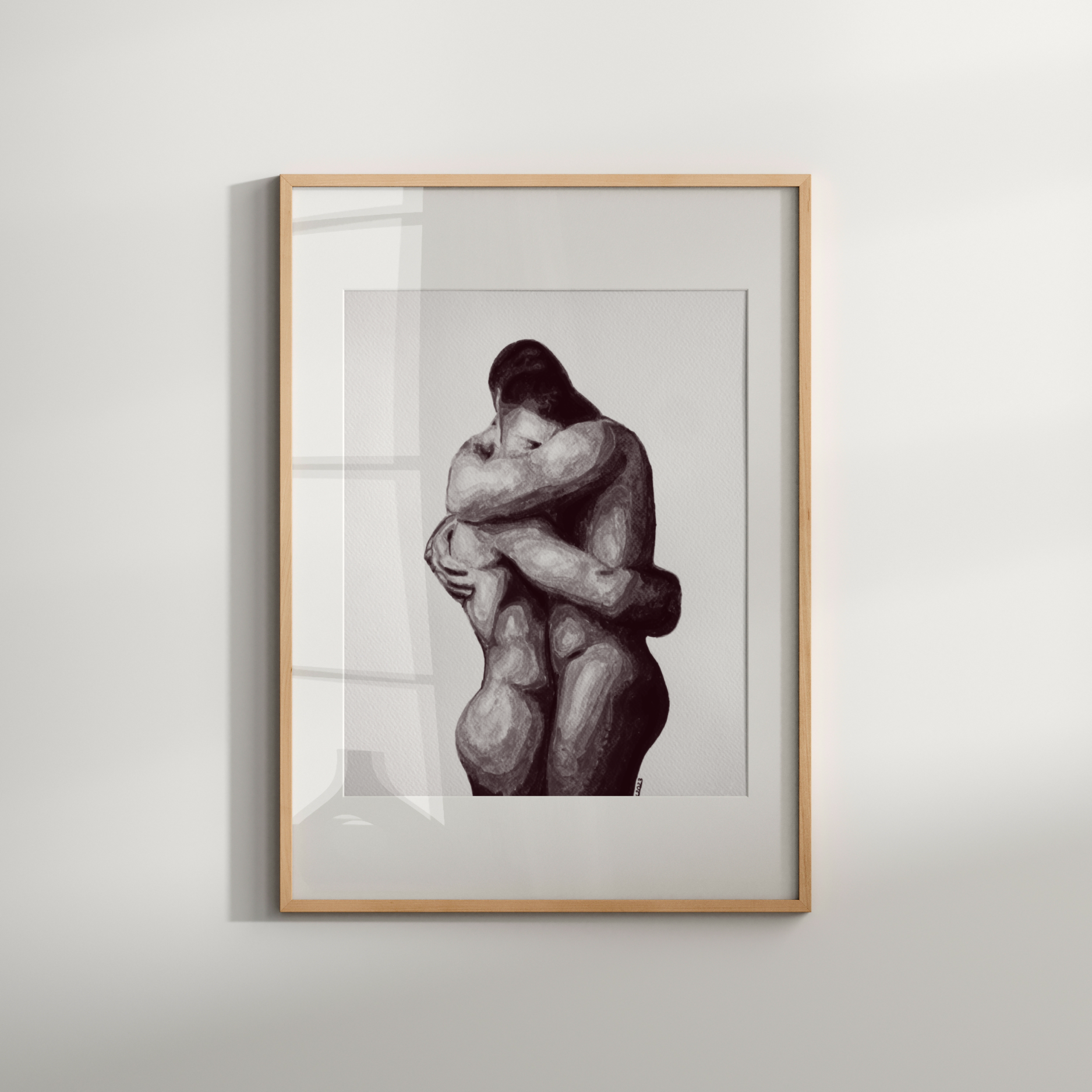 Framed artwork of two embracing figures on a white wall