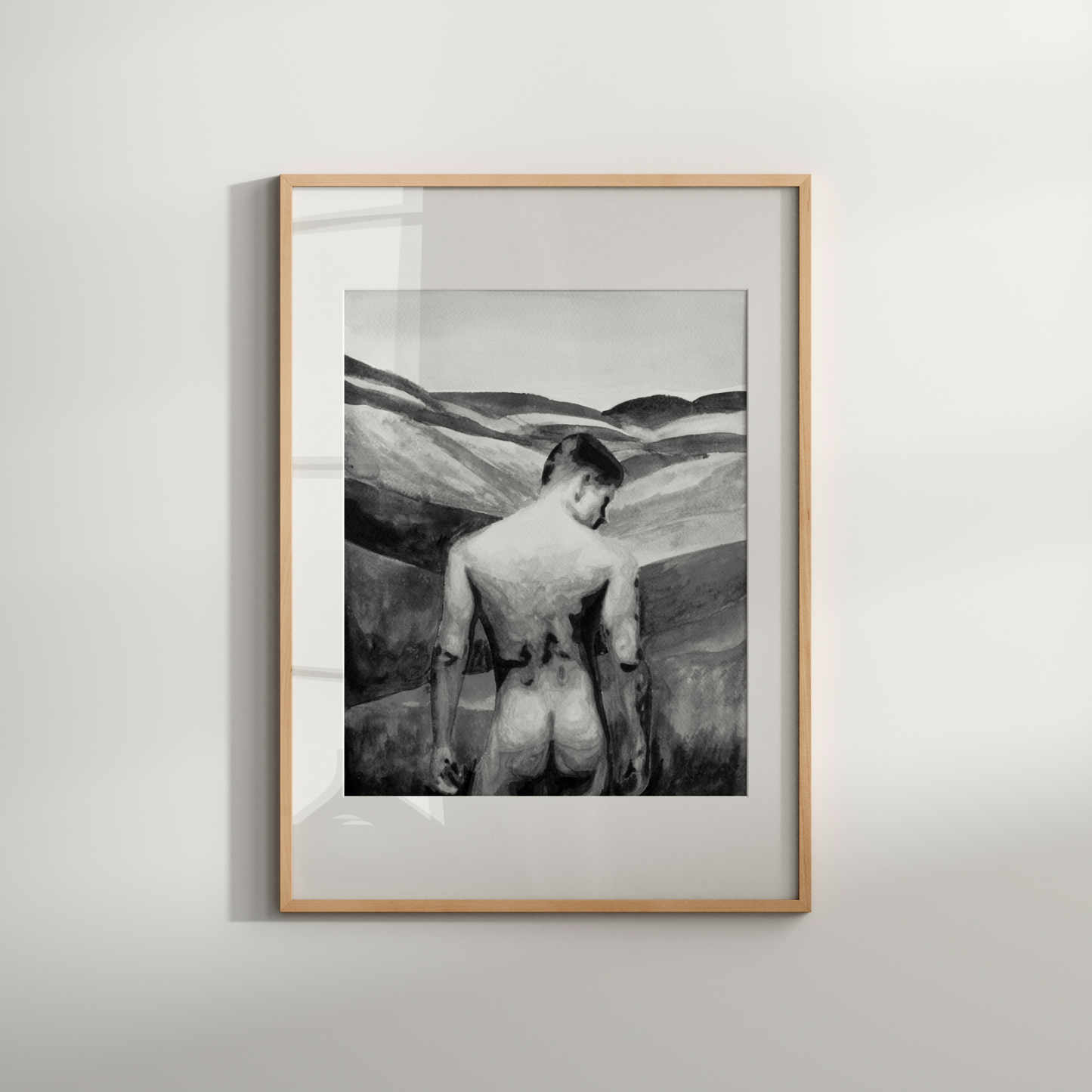 Framed black and white artwork of a person in a desert landscape on a light gray wall.