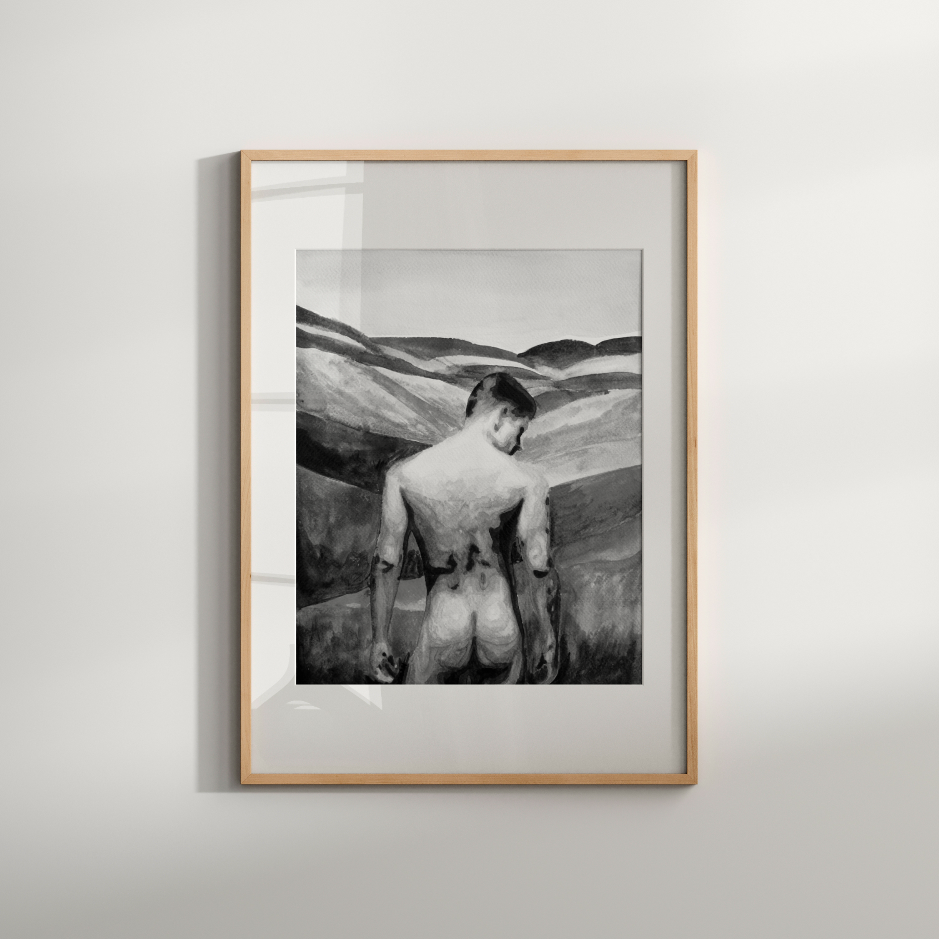 Framed black and white artwork of a person in a desert landscape on a light gray wall.