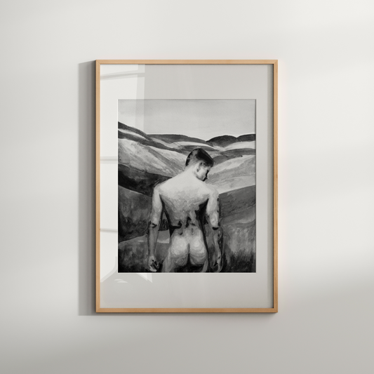 Framed black and white artwork of a person in a desert landscape on a light gray wall.