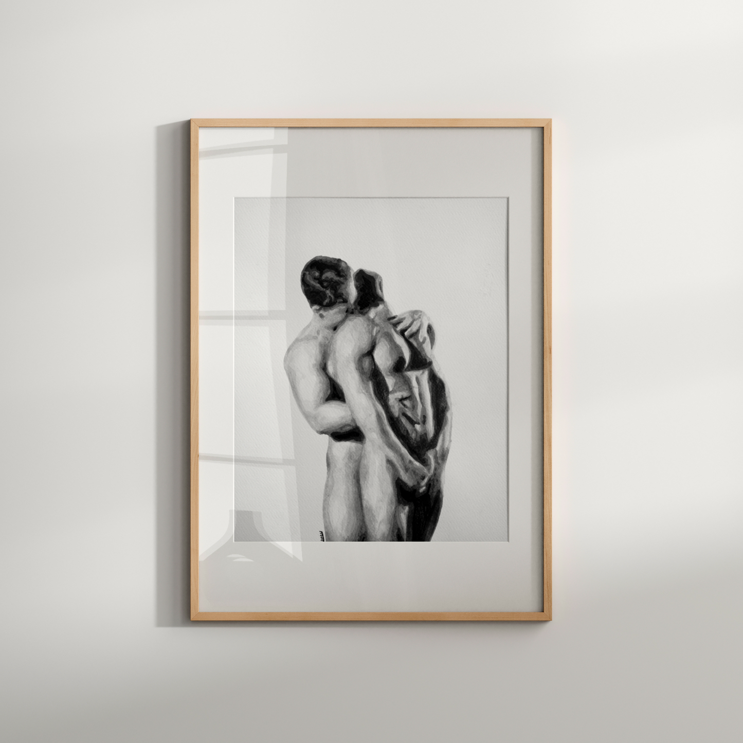 Framed black and white artwork of two people embracing on a light gray wall.