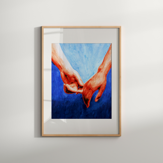 Framed artwork of two hands holding each other against a blue background on a white wall.