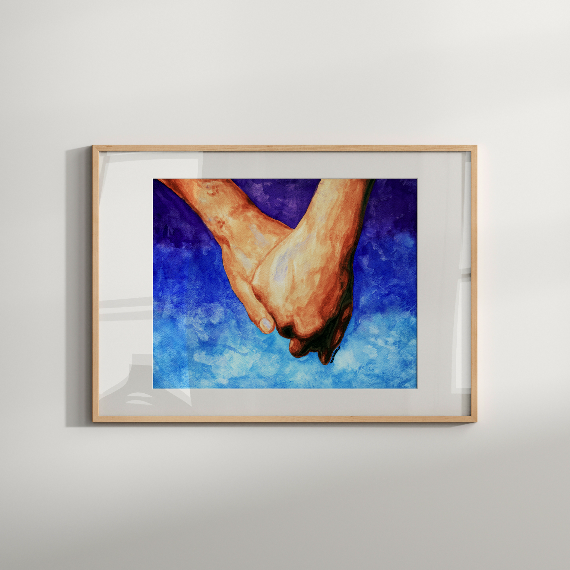 Framed artwork of hands on a blue background on a white wall