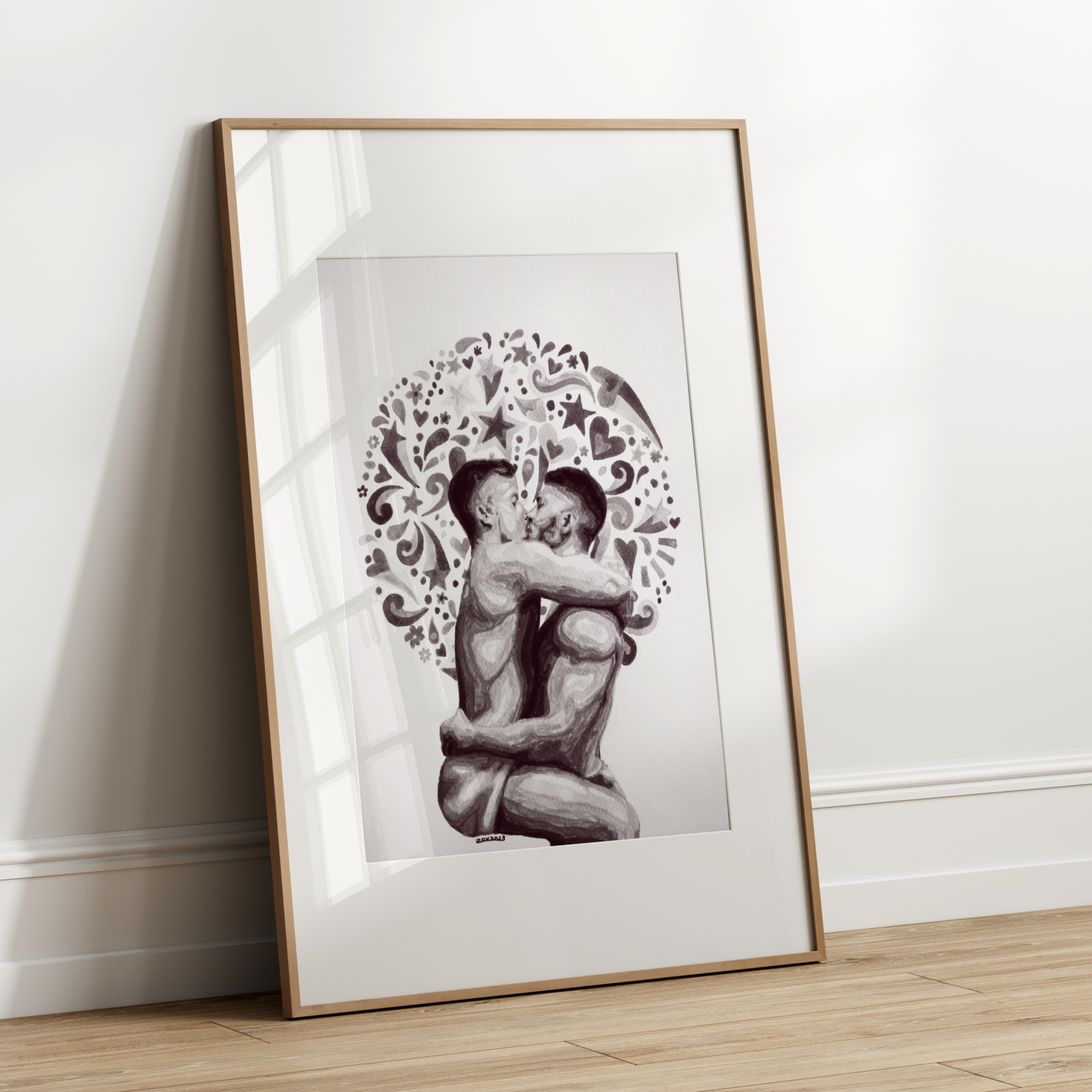 Framed artwork of two people embracing with decorative elements on a white wall.