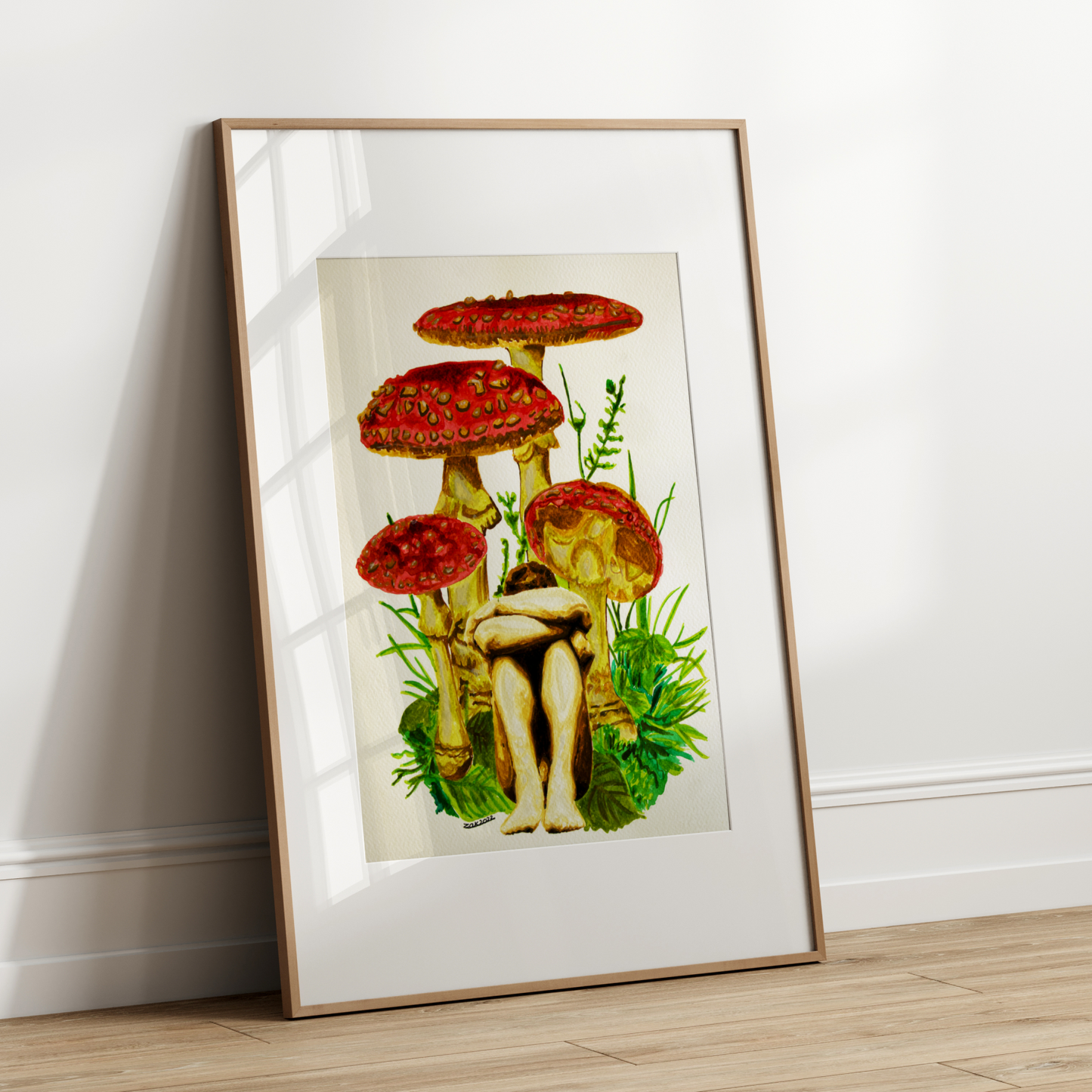 Framed artwork of a person sitting among red mushrooms on a white wall.