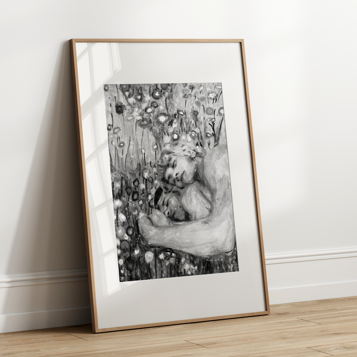 Framed black and white artwork leaning against a white wall.