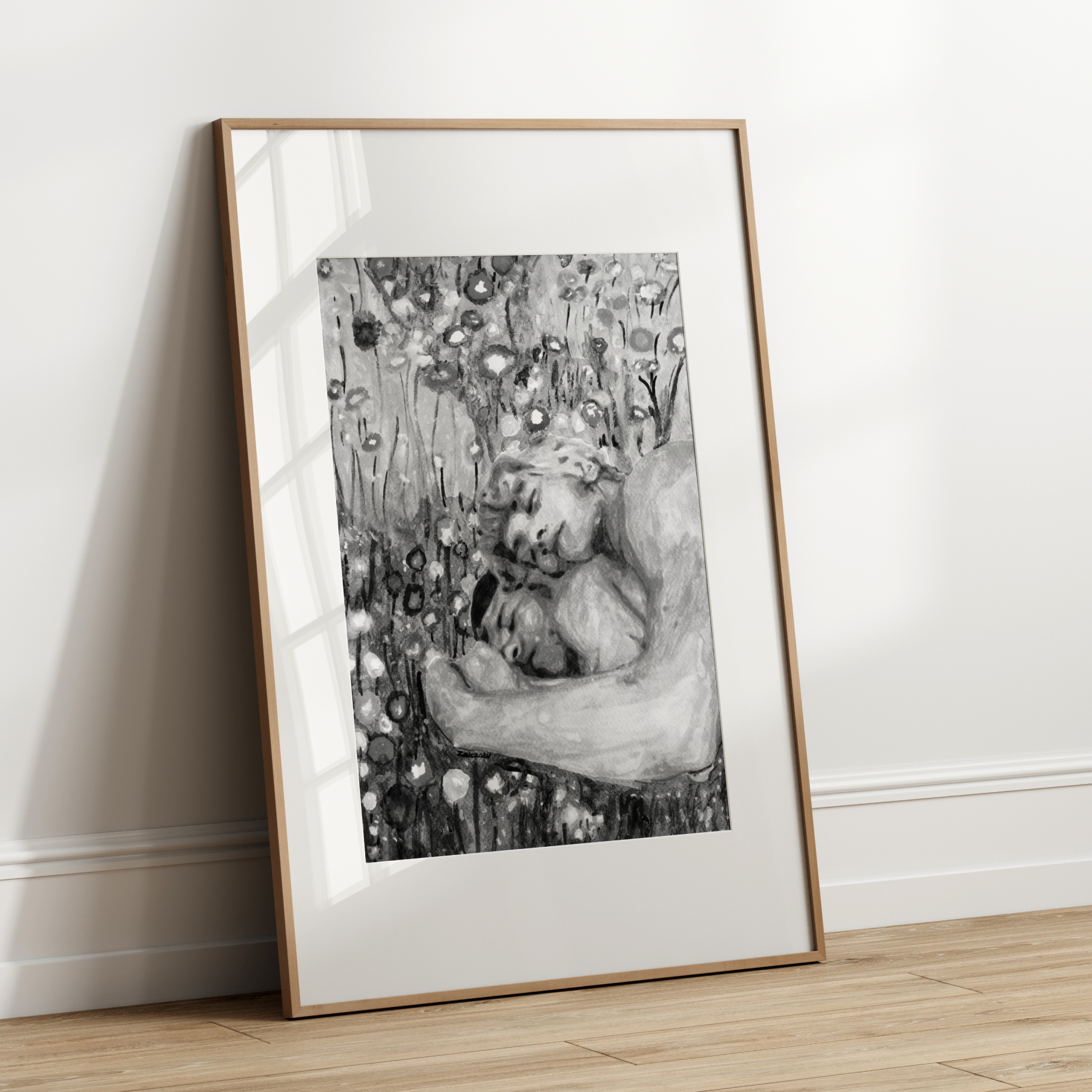 Framed black and white artwork leaning against a white wall.