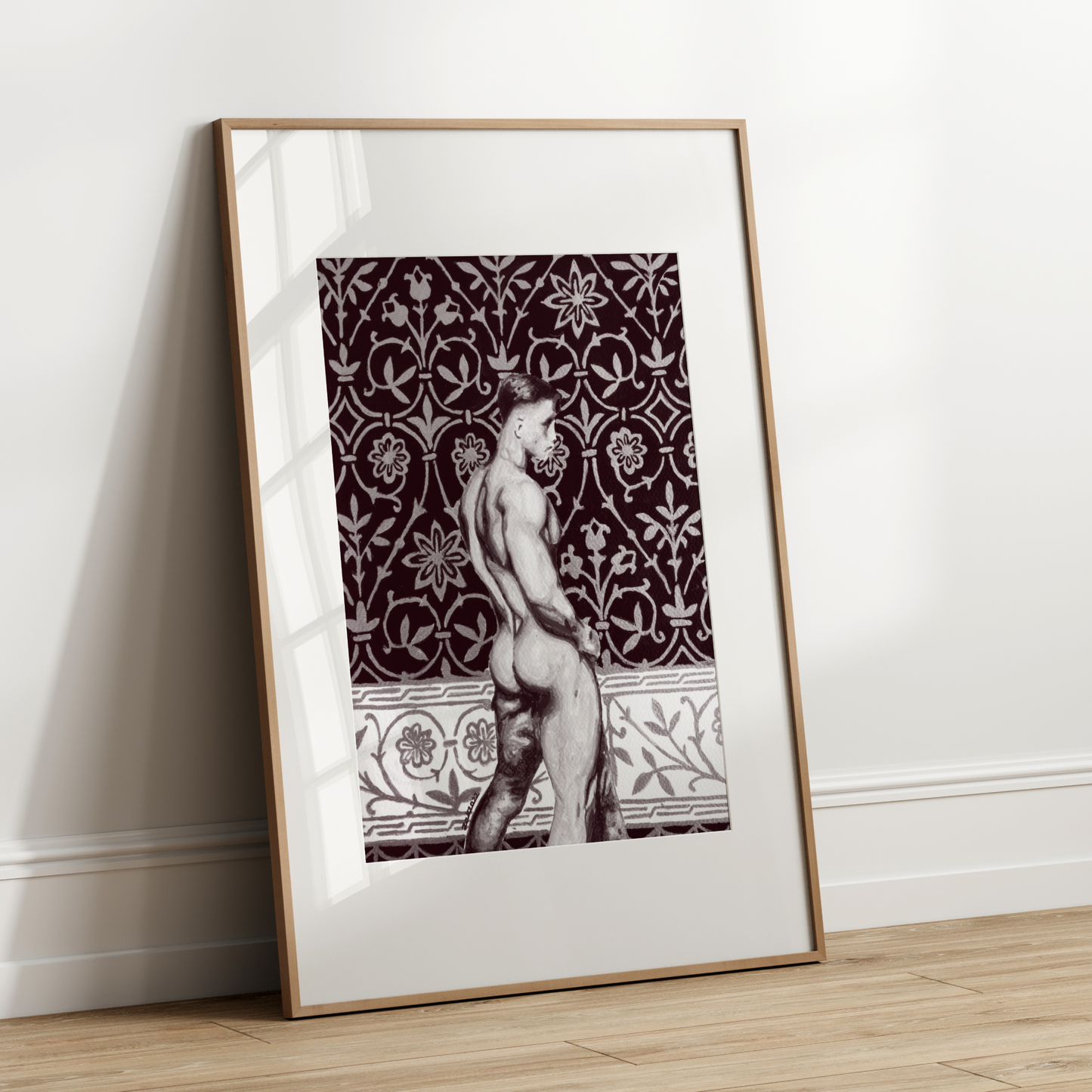 Framed artwork of a nude figure against a patterned background on a white wall.