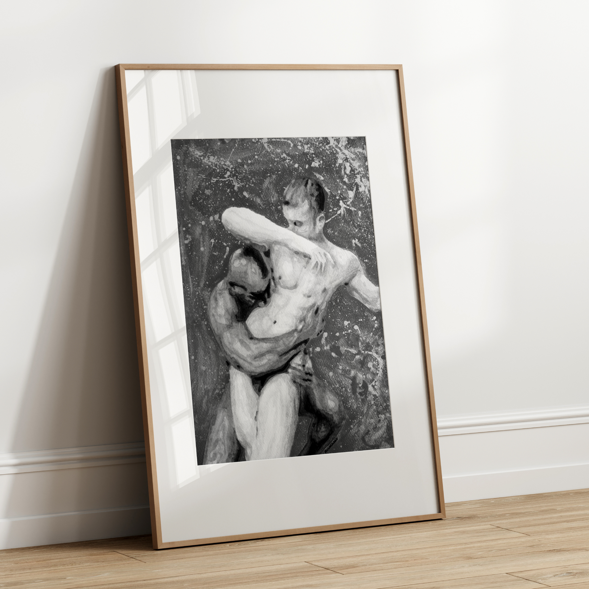 Framed black and white artwork of a nude figure leaning against a textured wall on a wooden floor.