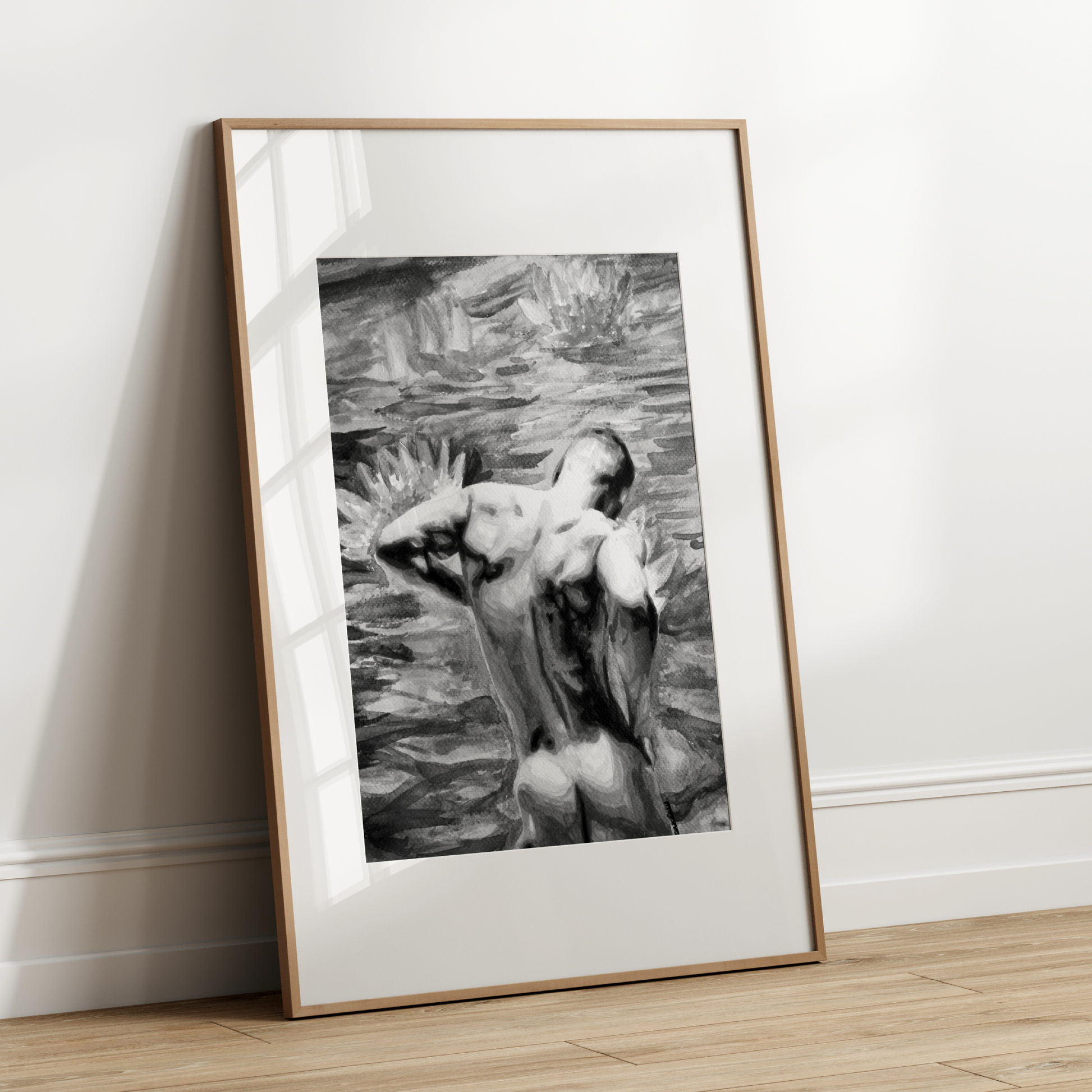 Framed black and white artwork of a nude figure leaning over water on a white wall.