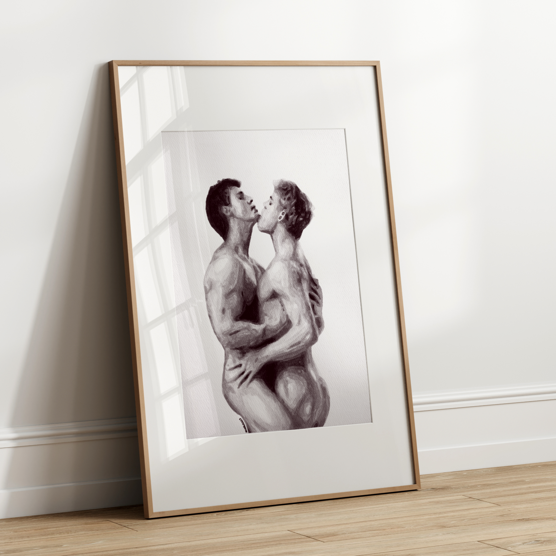 Framed black and white artwork of two people embracing on a white wall.