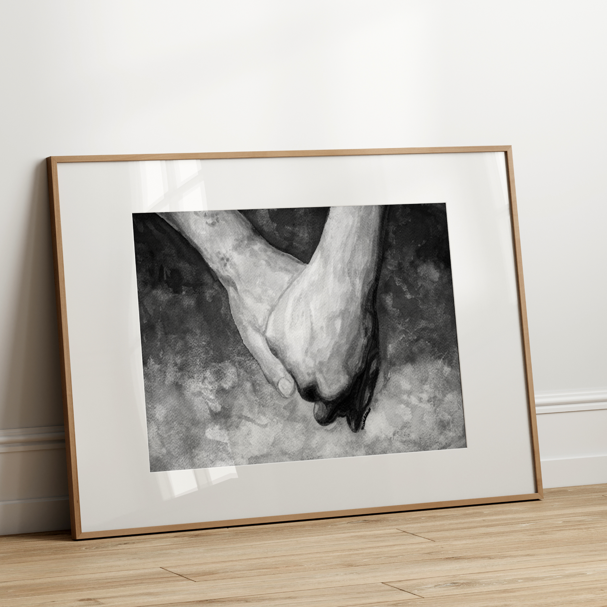 Framed black and white photograph of two feet on a wooden floor with a white wall background