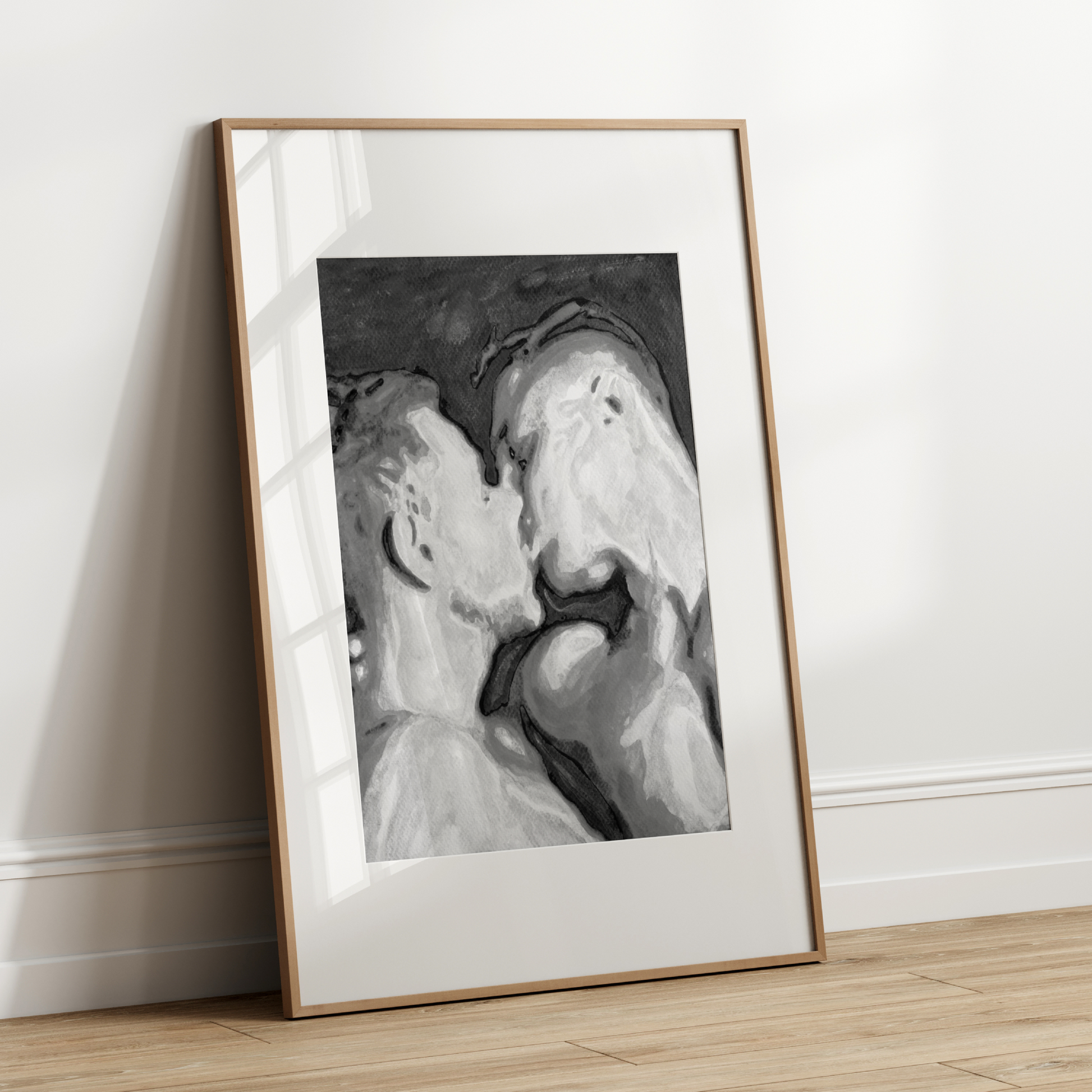 Framed artwork of two faces kissing on a white wall.