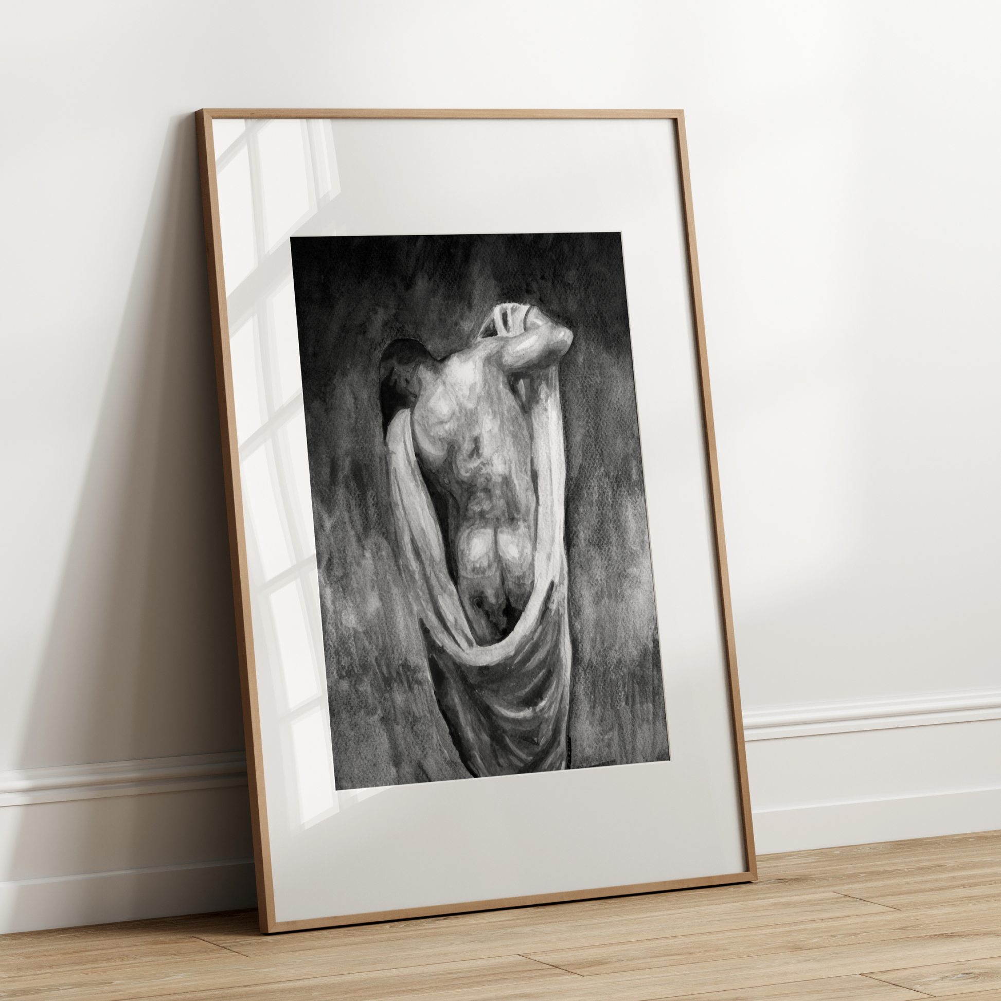 Framed black and white artwork leaning against a white wall.