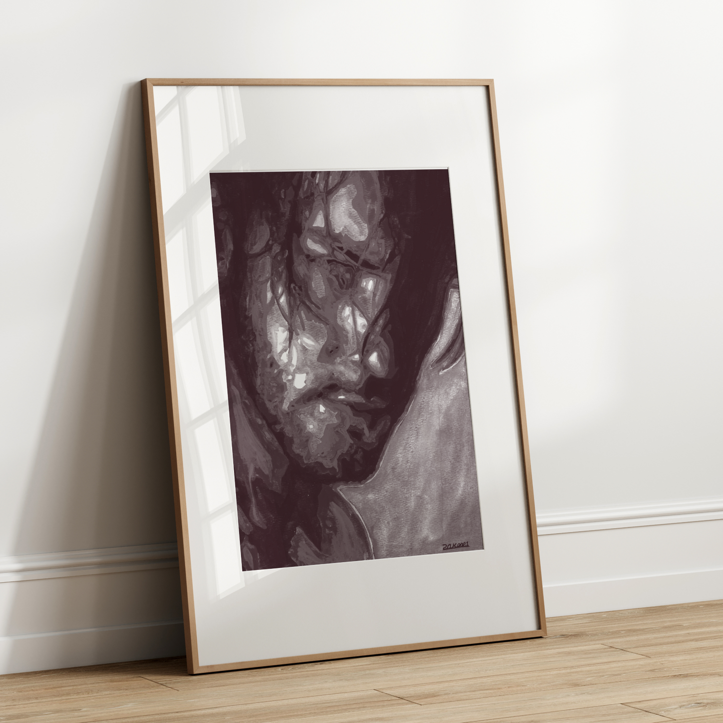 Framed artwork leaning against a white wall on a wooden floor