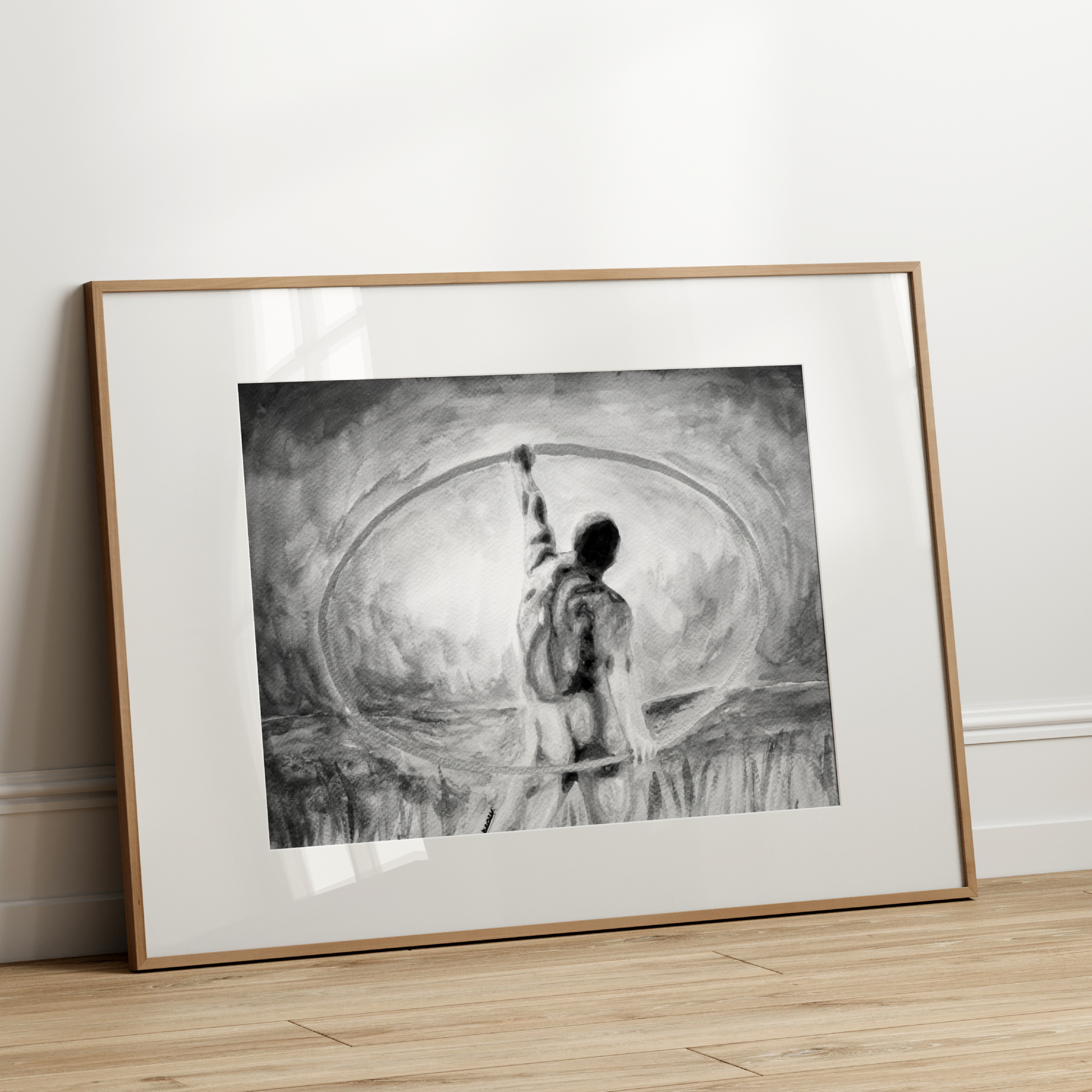 Framed black and white artwork of a person on a wooden floor against a white wall