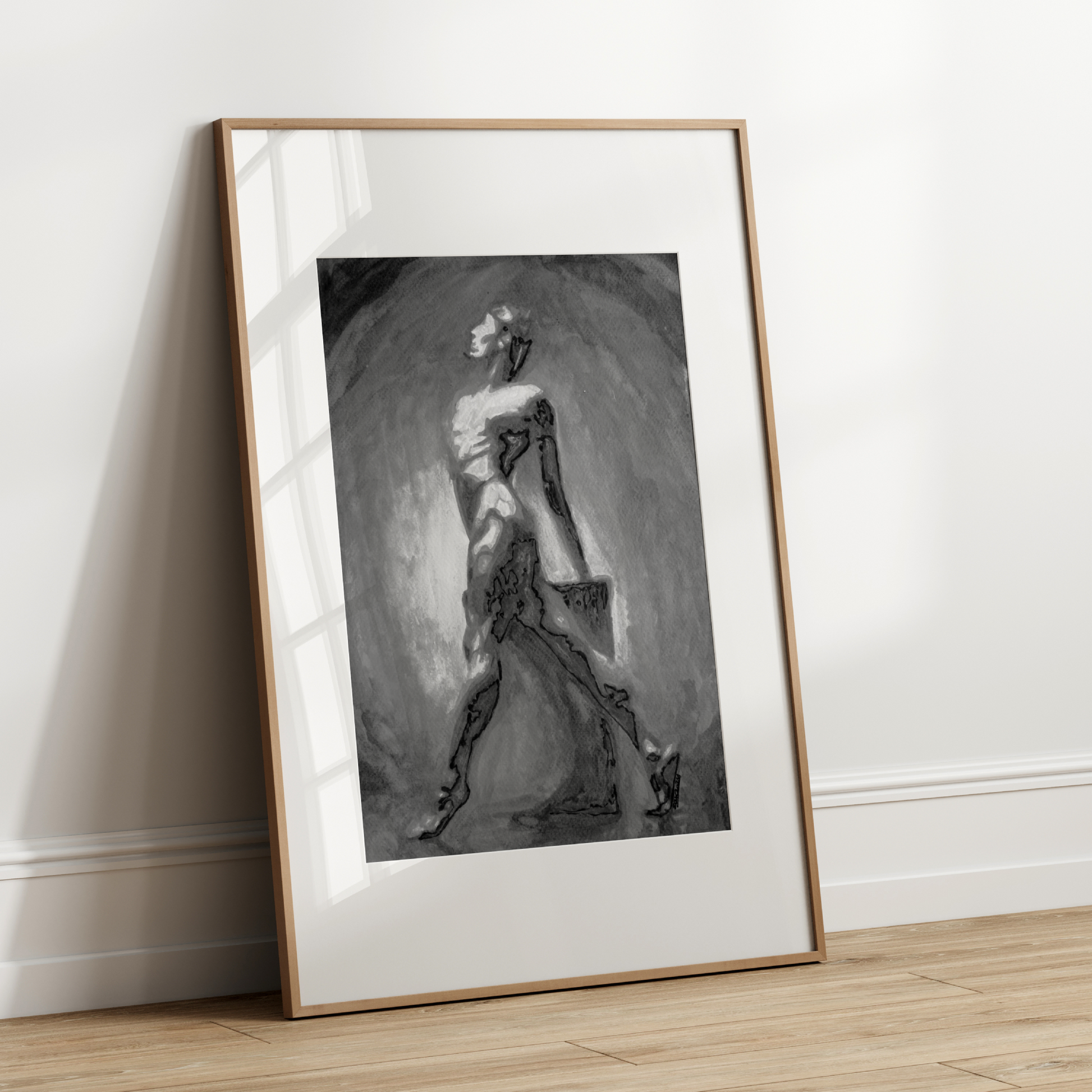 Framed black and white artwork leaning against a white wall.