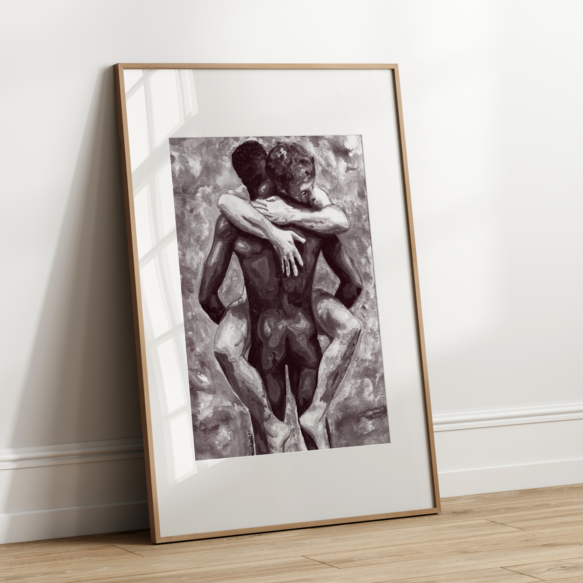 Framed black and white artwork of two people embracing on a white wall.