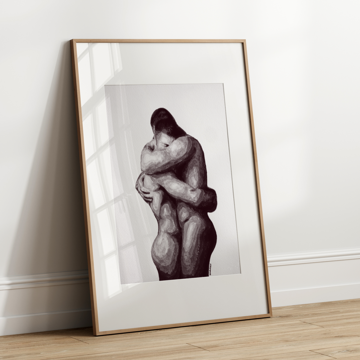 Framed artwork of two people embracing on a white wall.