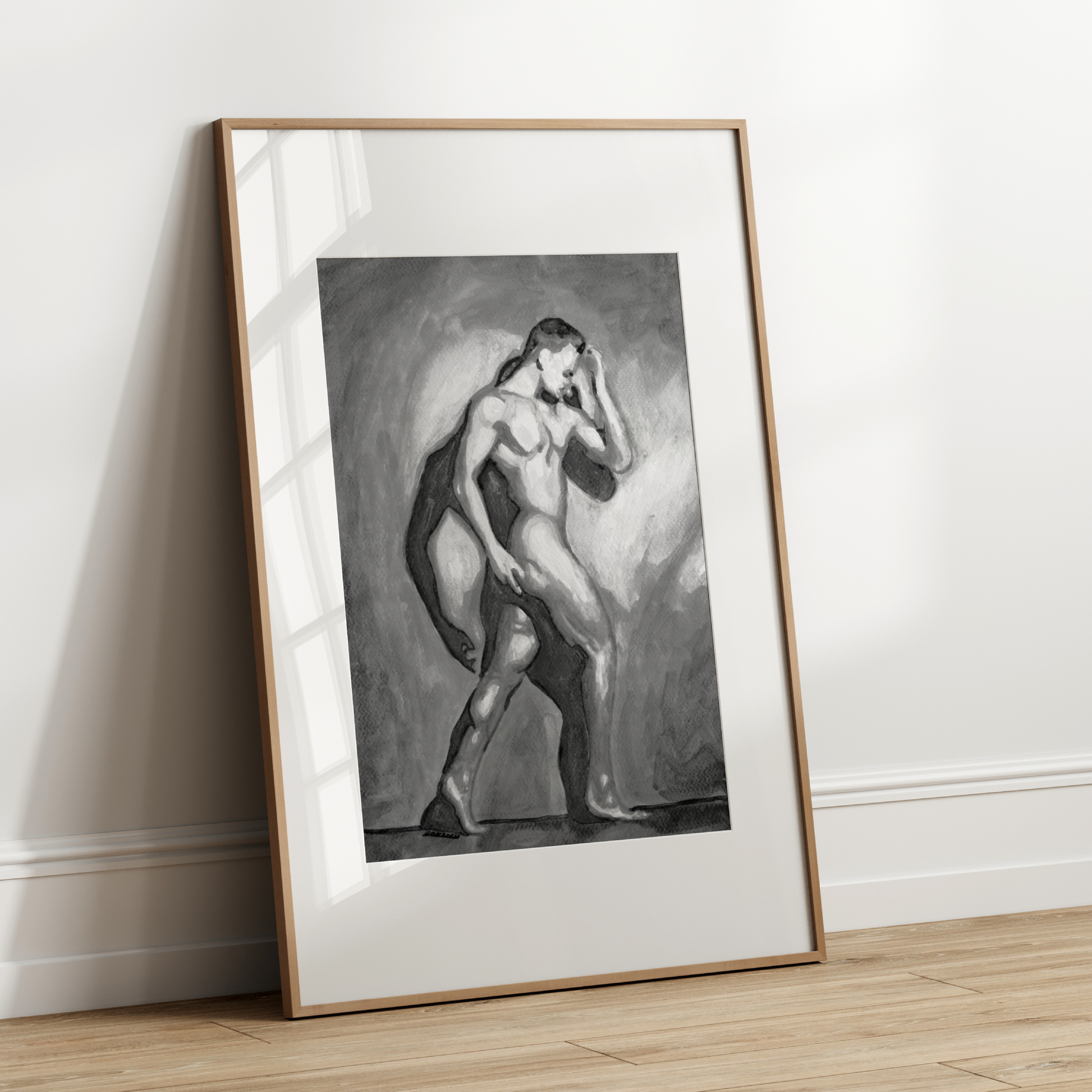 Framed black and white artwork of a nude figure leaning against a wall.