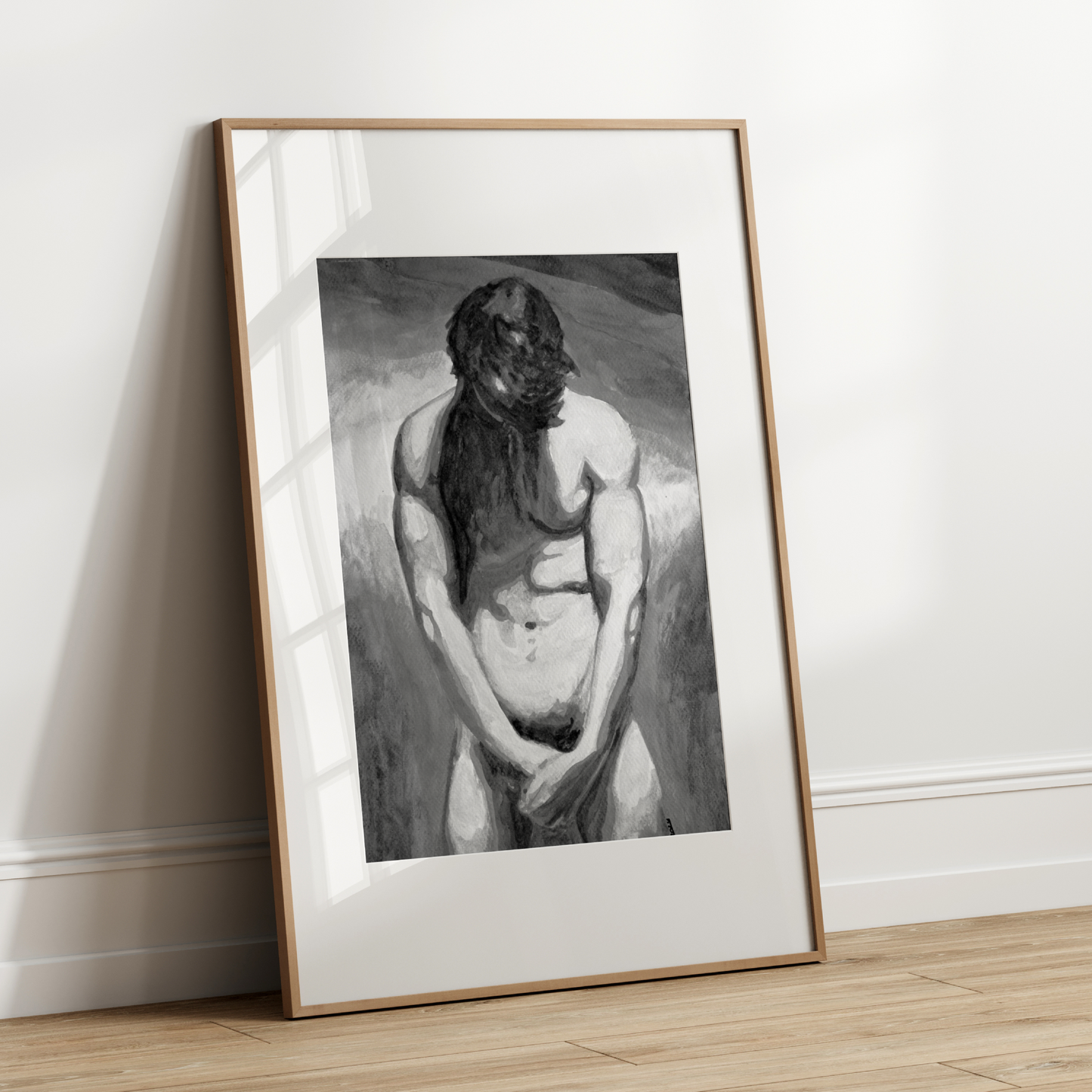 Framed black and white artwork of a nude figure leaning against a wall.