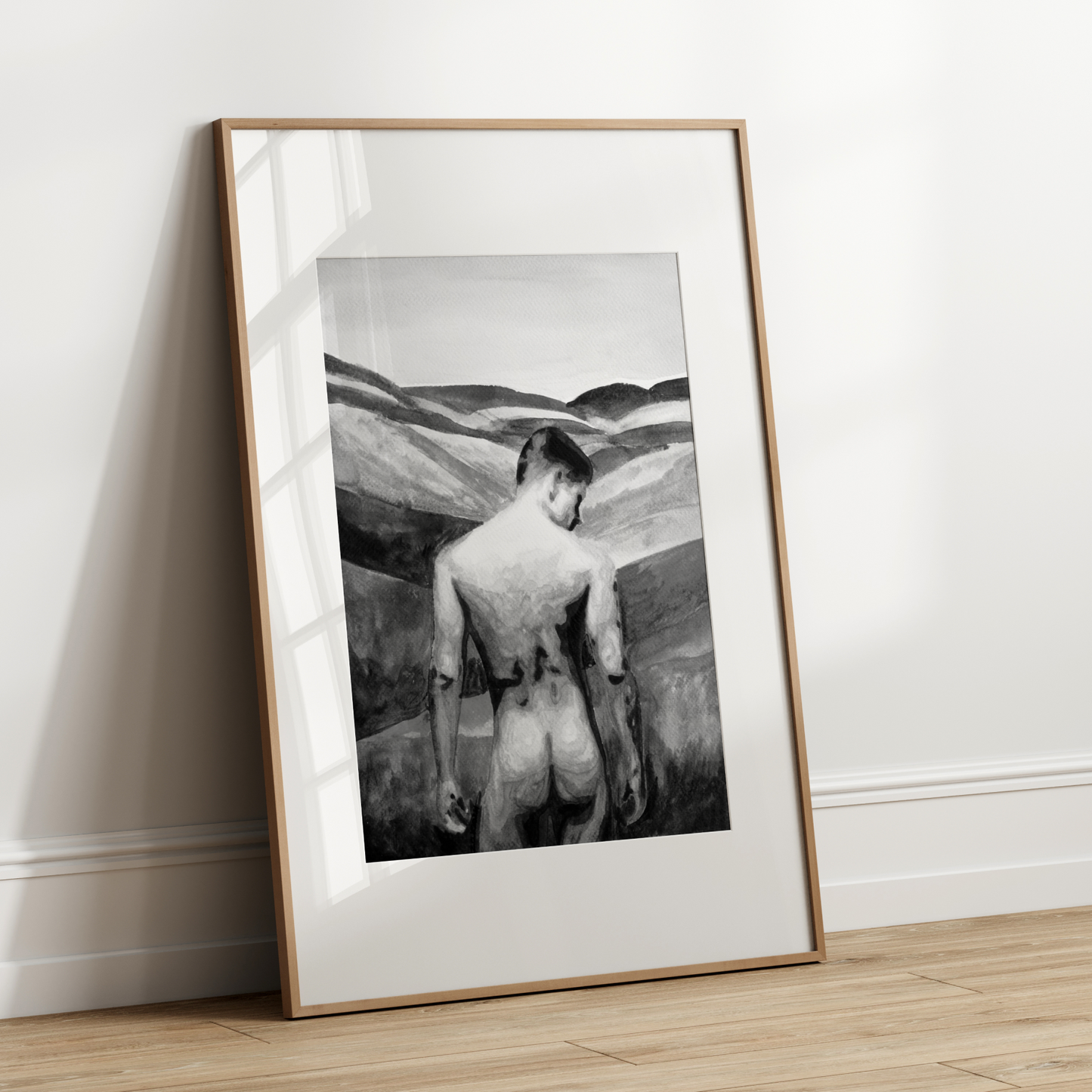 Framed black and white artwork of a nude figure on a plain wall.