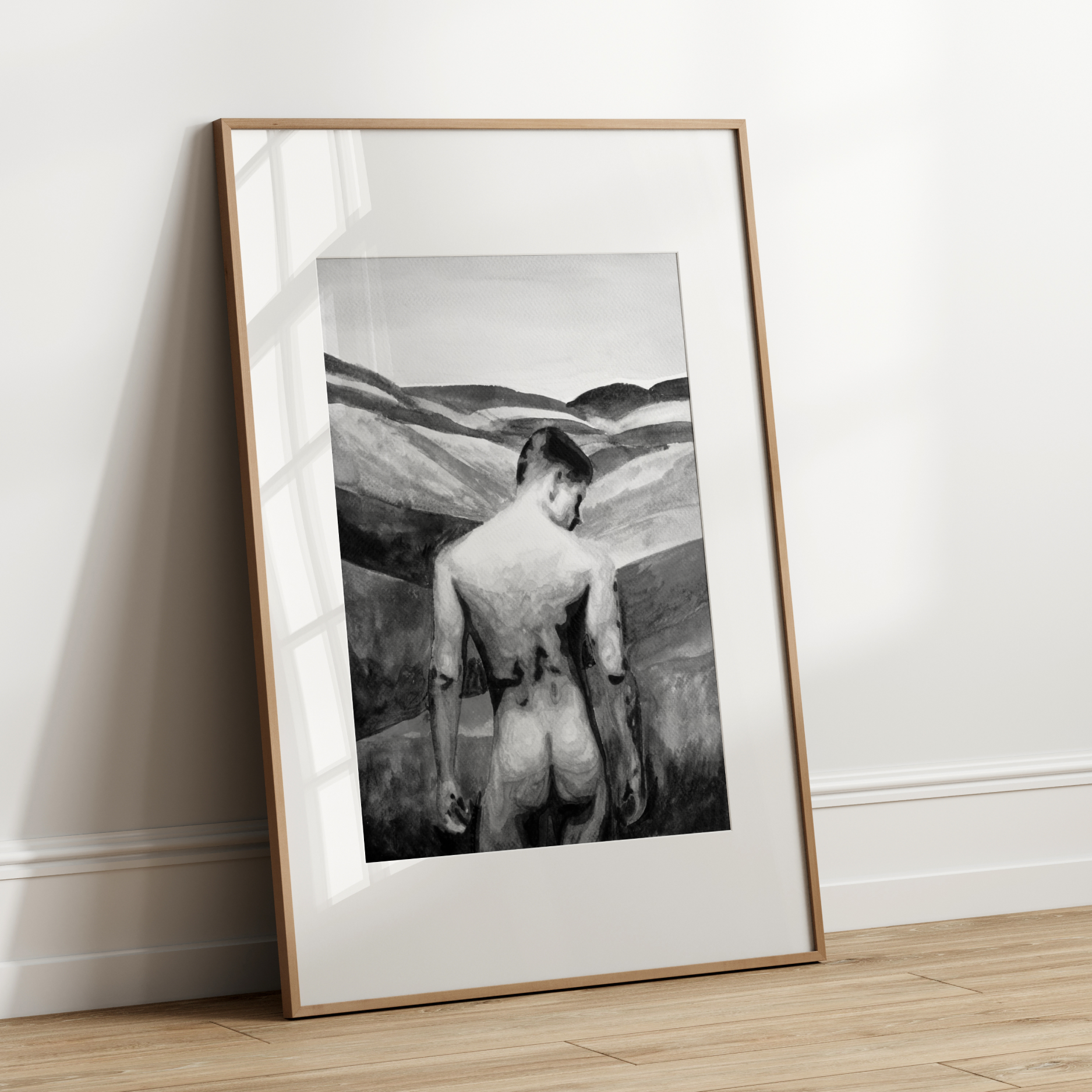 Framed black and white artwork of a nude figure on a plain wall.