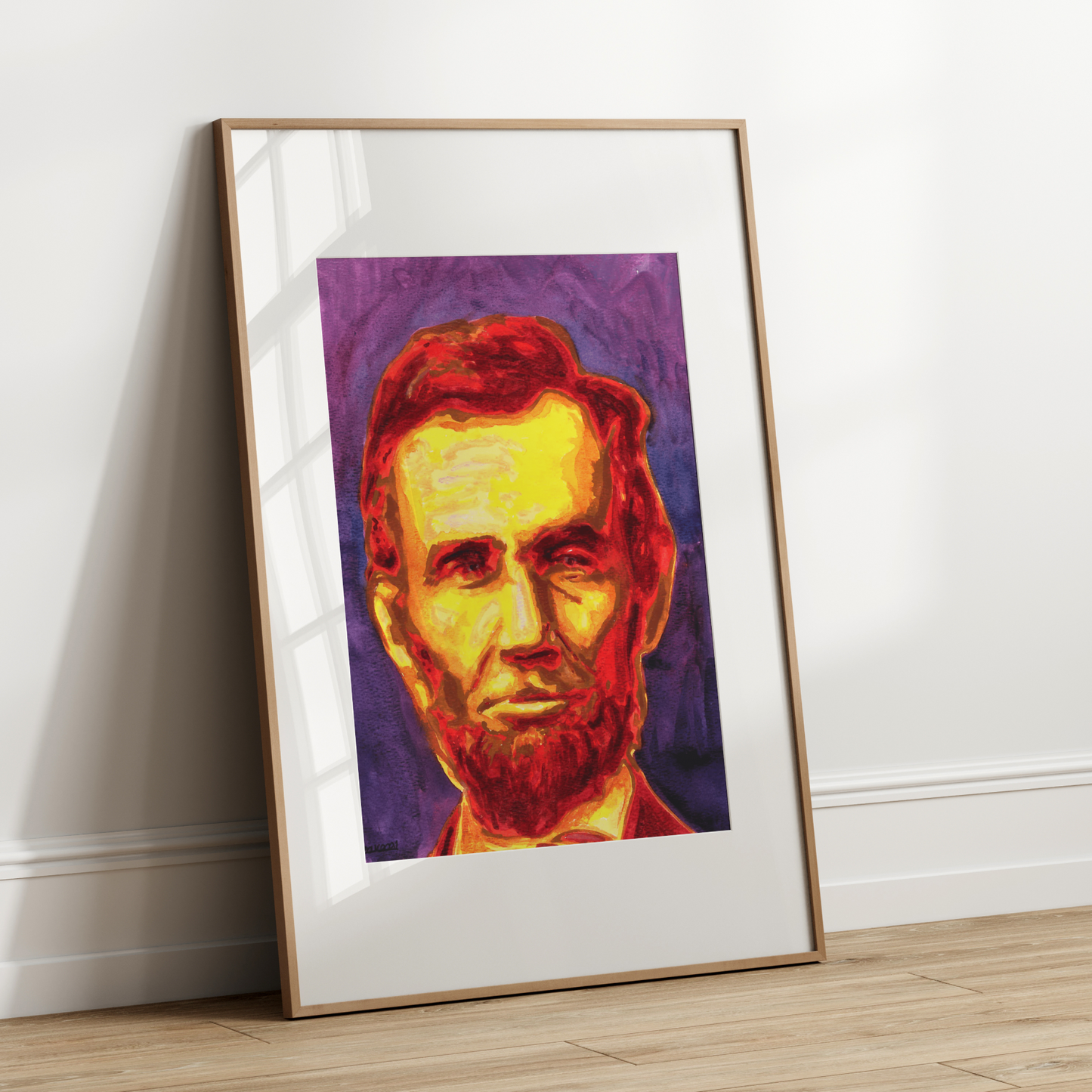Framed colorful portrait of a historical figure leaning against a white wall.