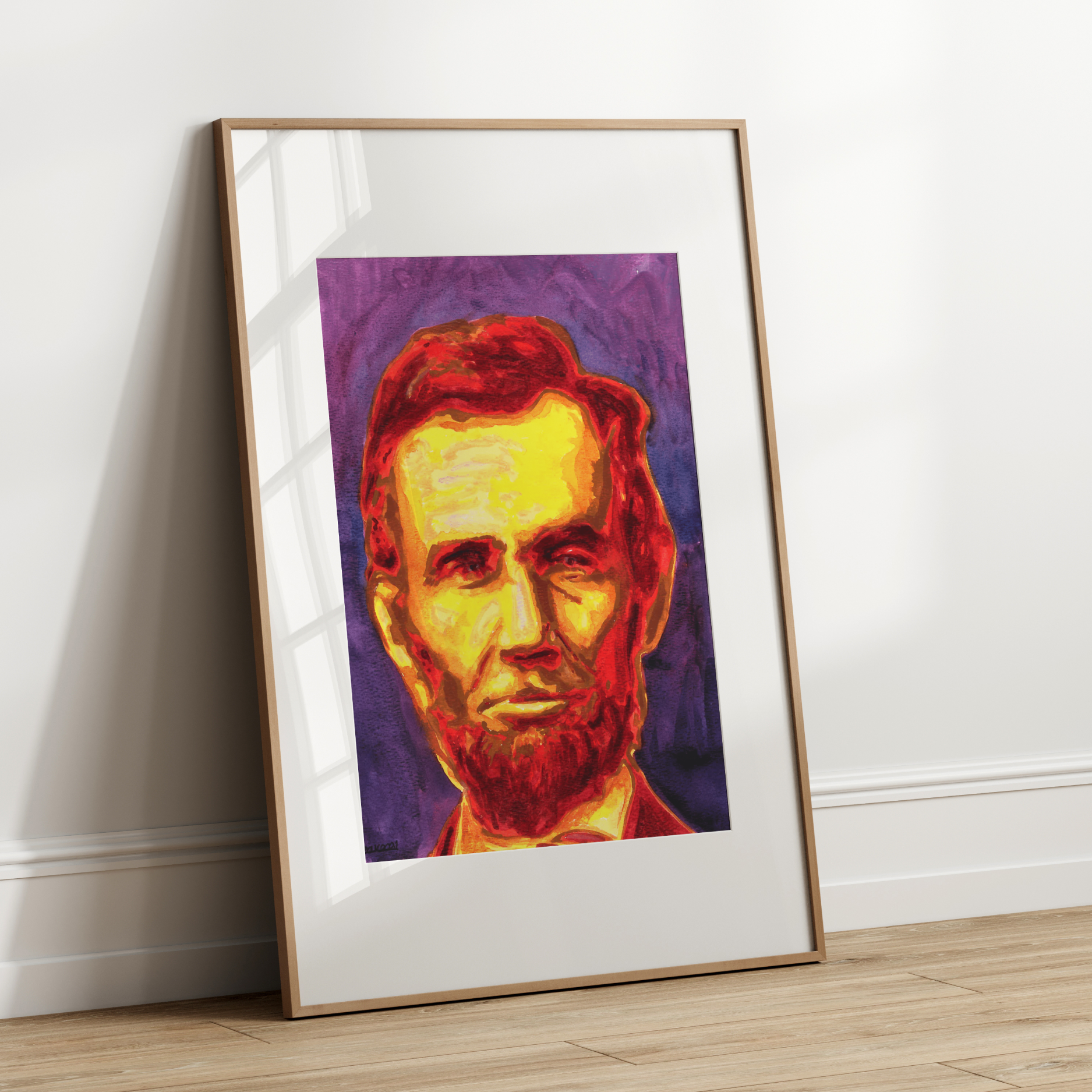 Framed colorful portrait of a historical figure leaning against a white wall.