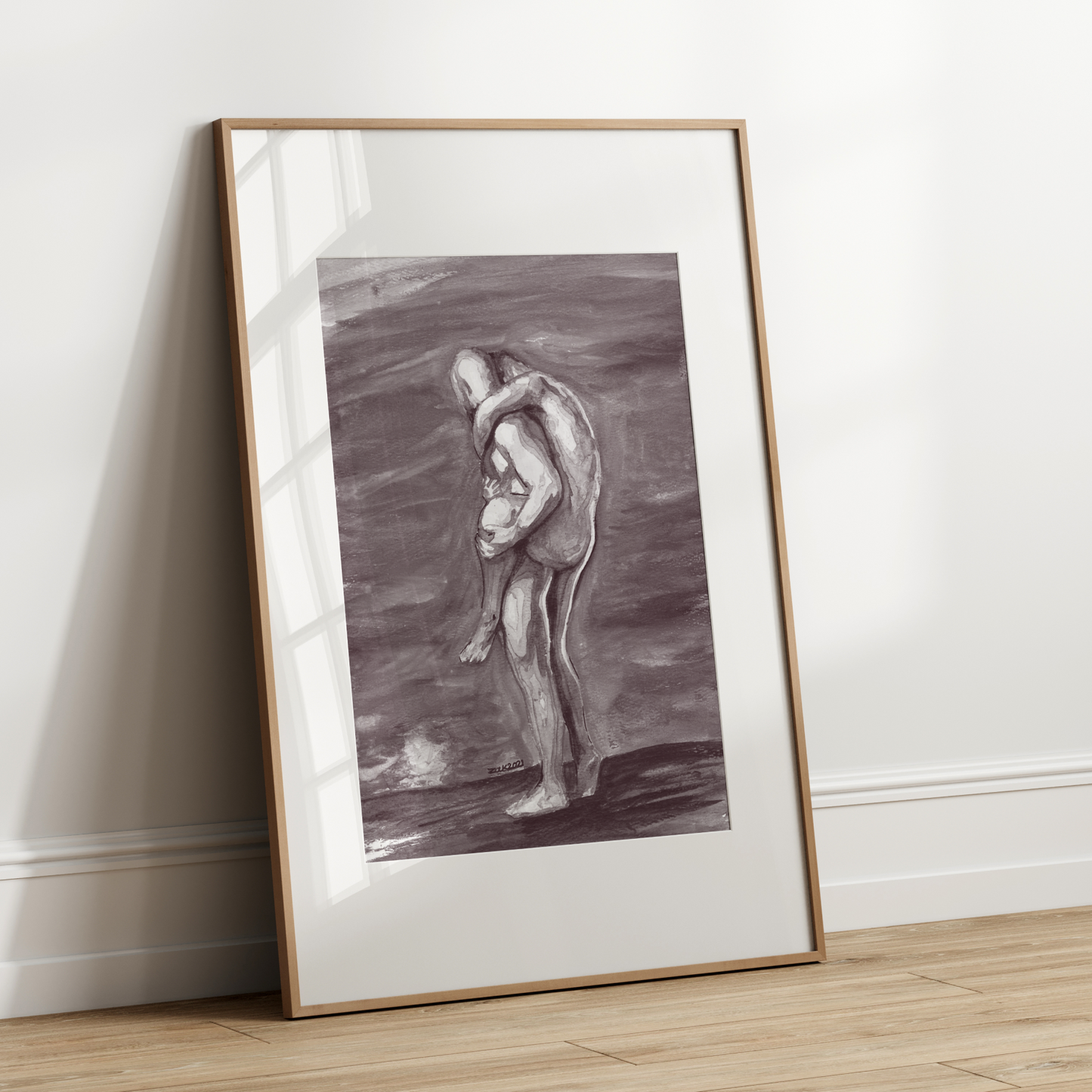 Framed artwork of two figures embracing on a white wall.