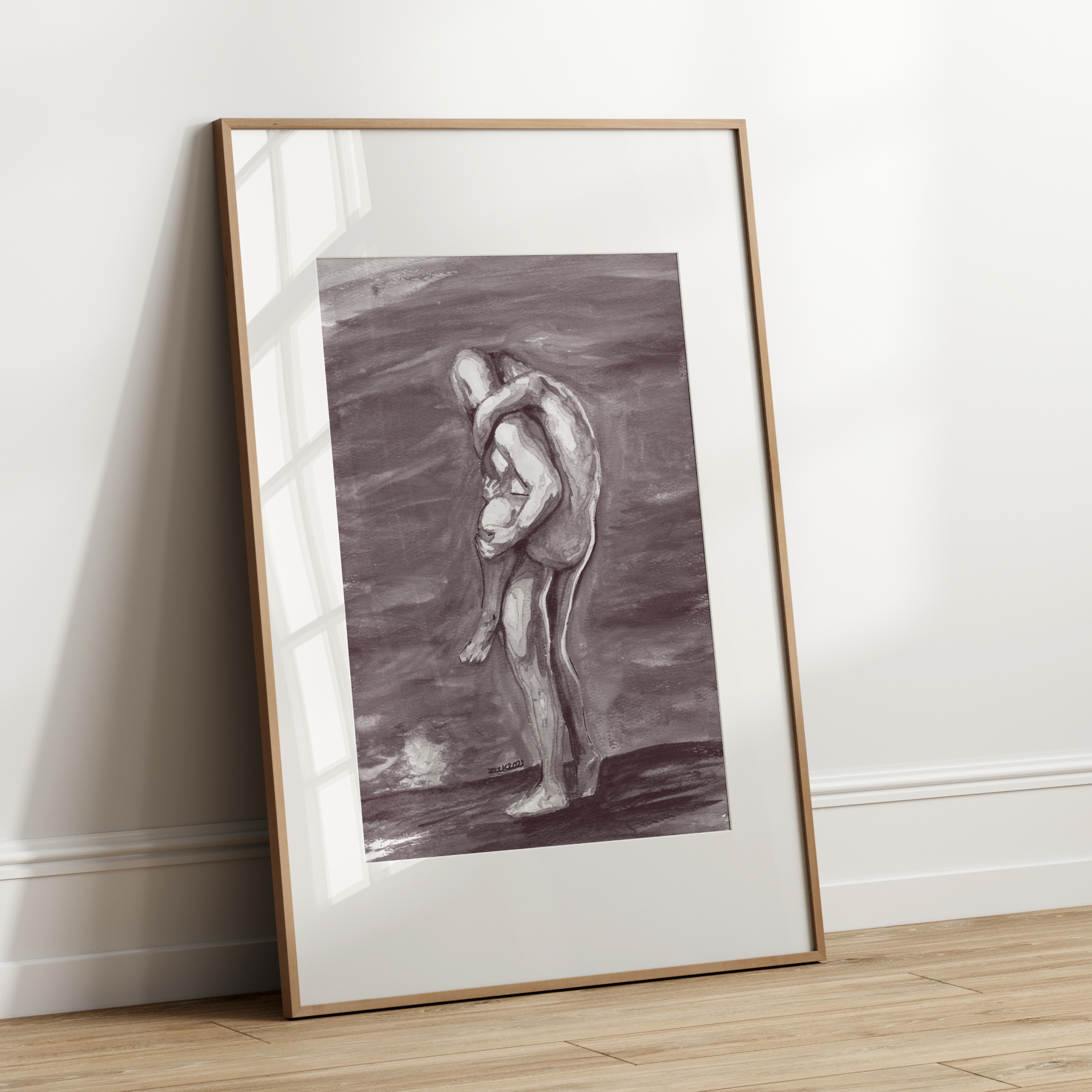 Framed artwork of two figures embracing on a white wall.