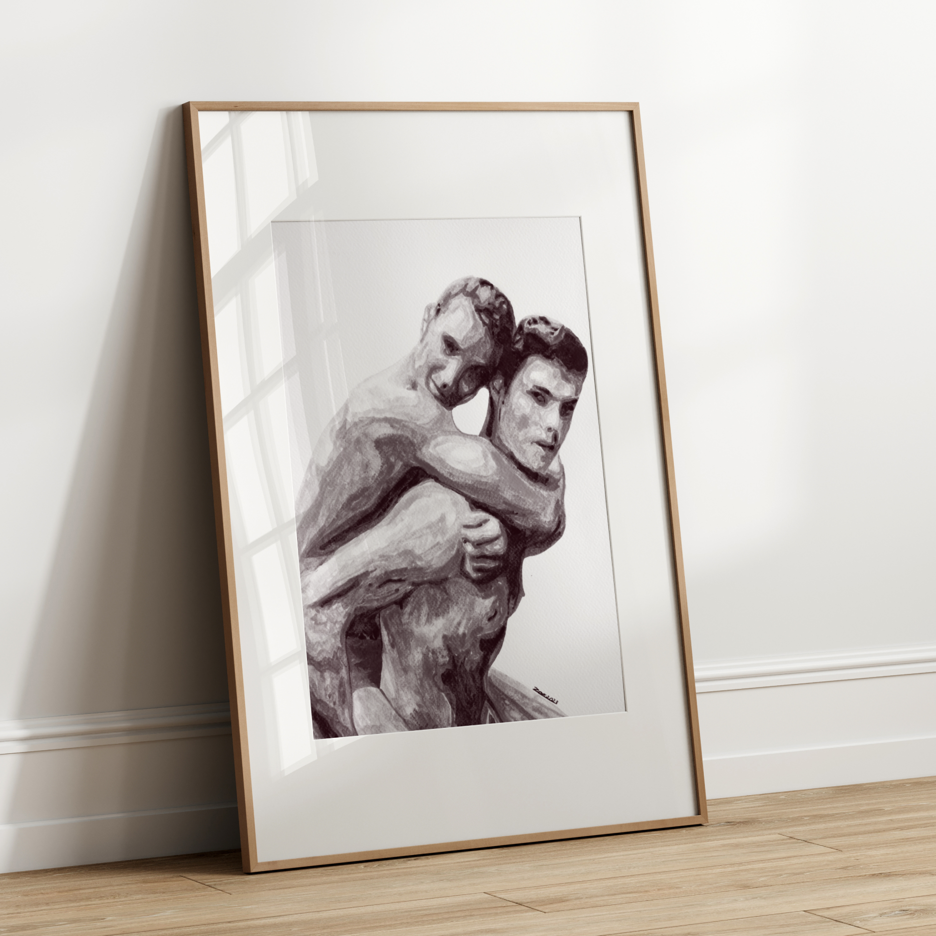 Framed black and white photograph of two people embracing on a wooden floor against a white wall.