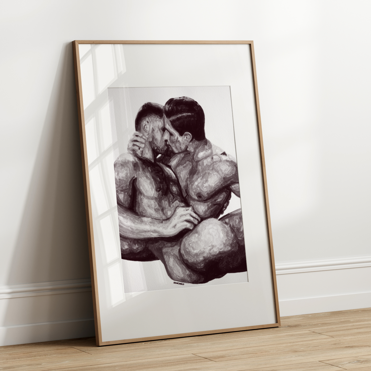 Framed black and white artwork of two people embracing on a white wall.