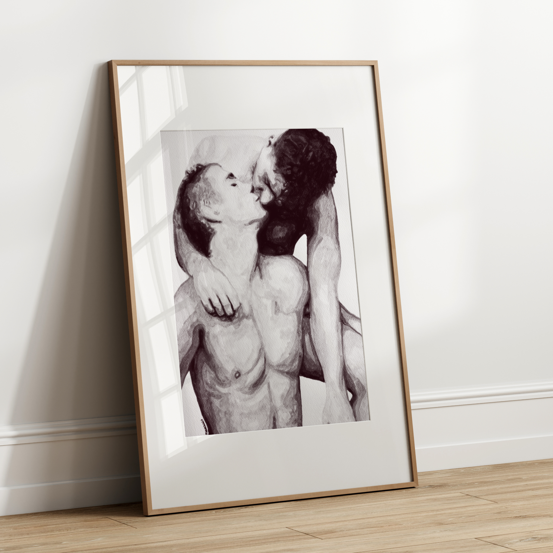 Framed black and white artwork of two people embracing on a white wall.