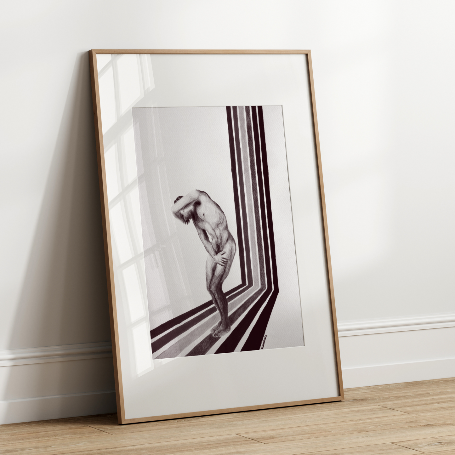 Framed black and white artwork leaning against a white wall.