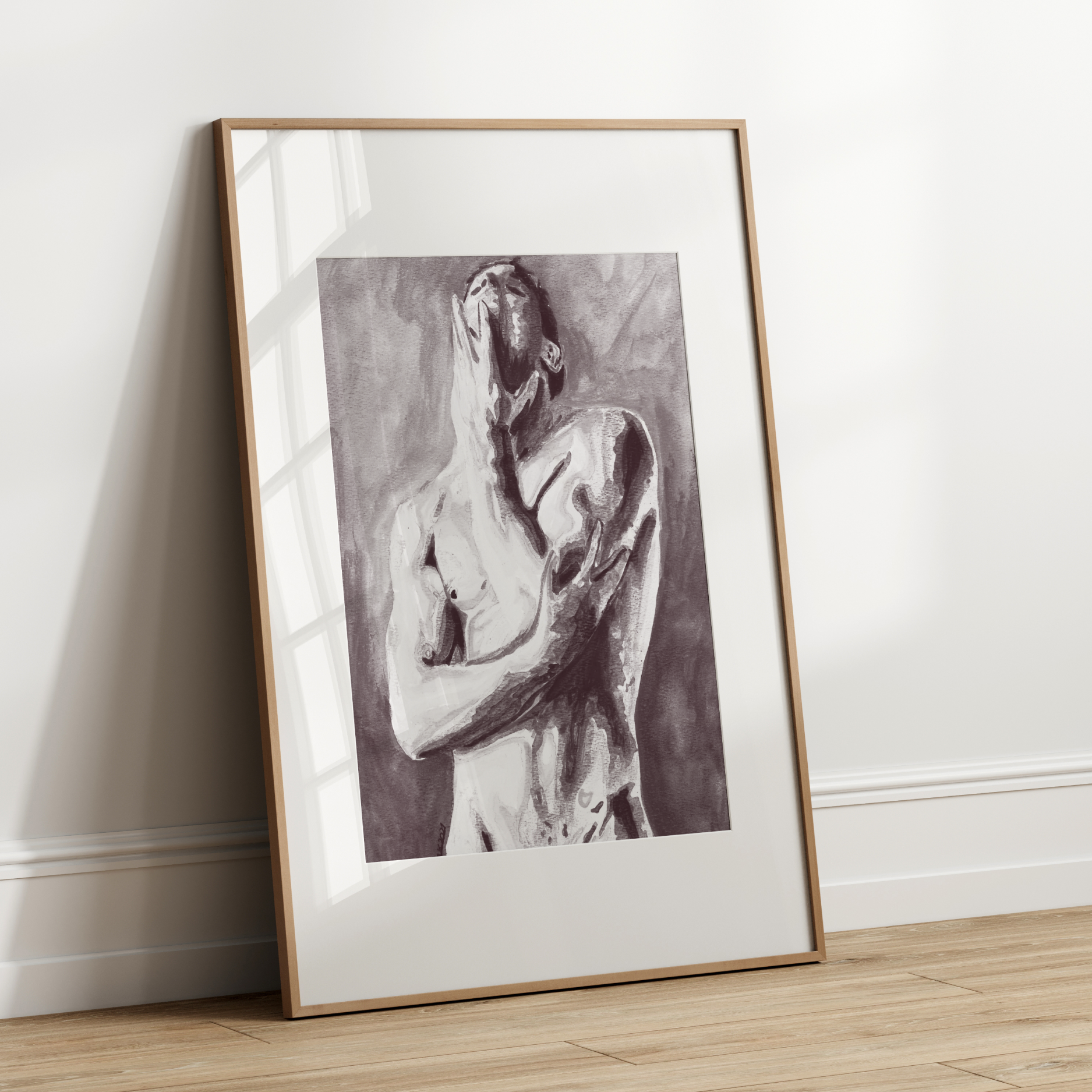Framed black and white artwork of a nude figure leaning against a white wall.
