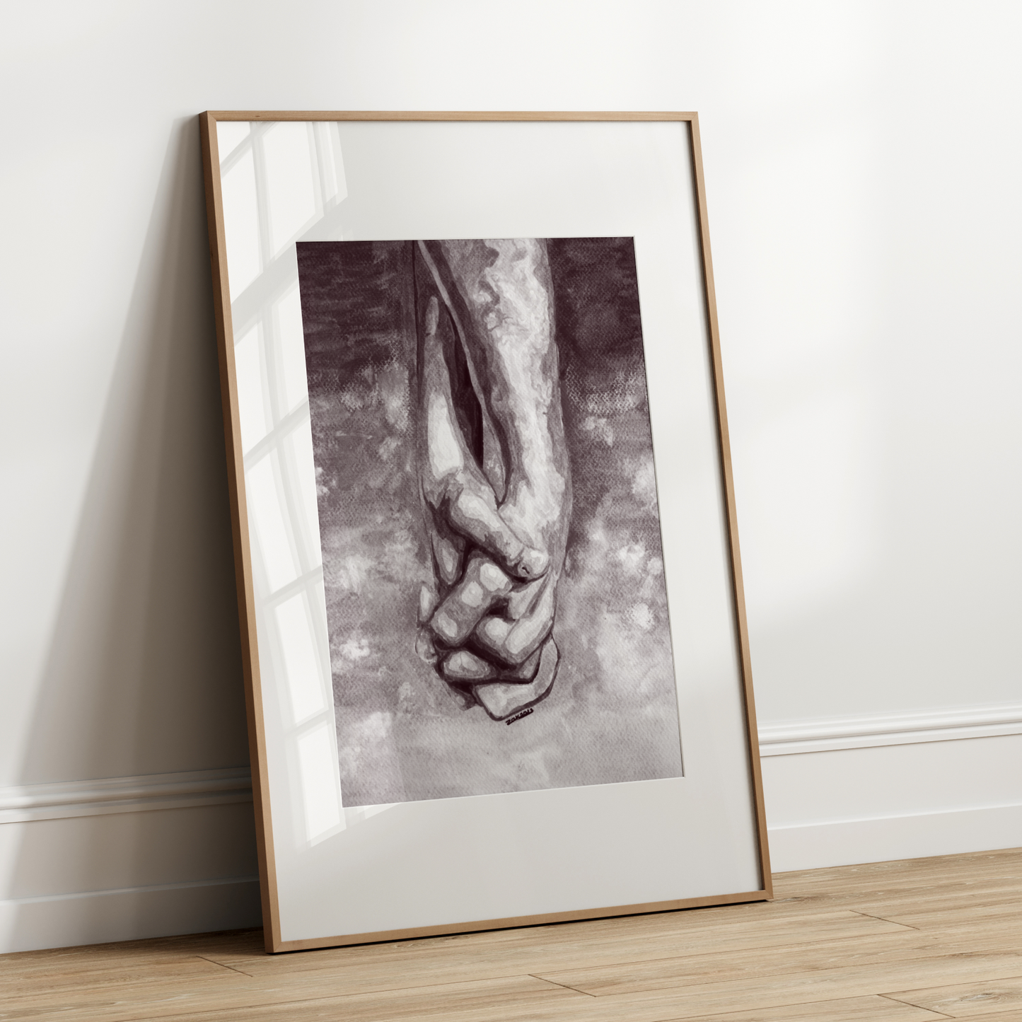 Framed artwork of two hands holding each other on a white wall.