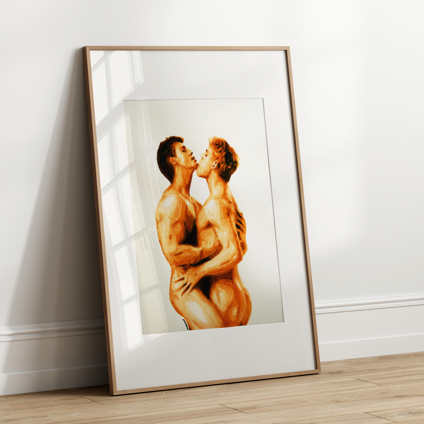 Framed artwork of two nude figures embracing on a white wall.