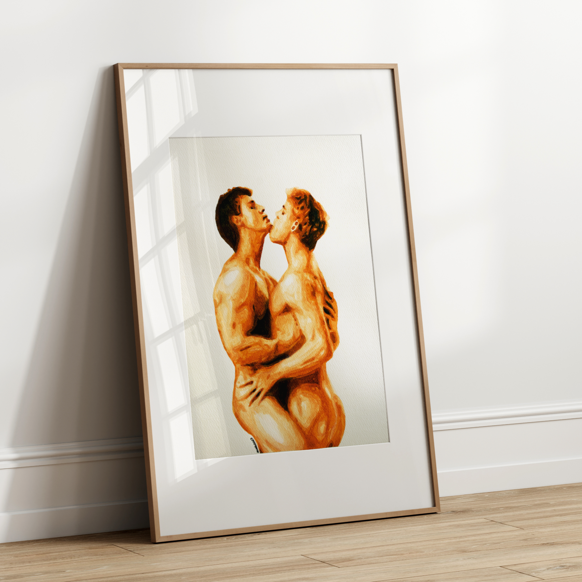 Framed artwork of two nude figures embracing on a white wall.
