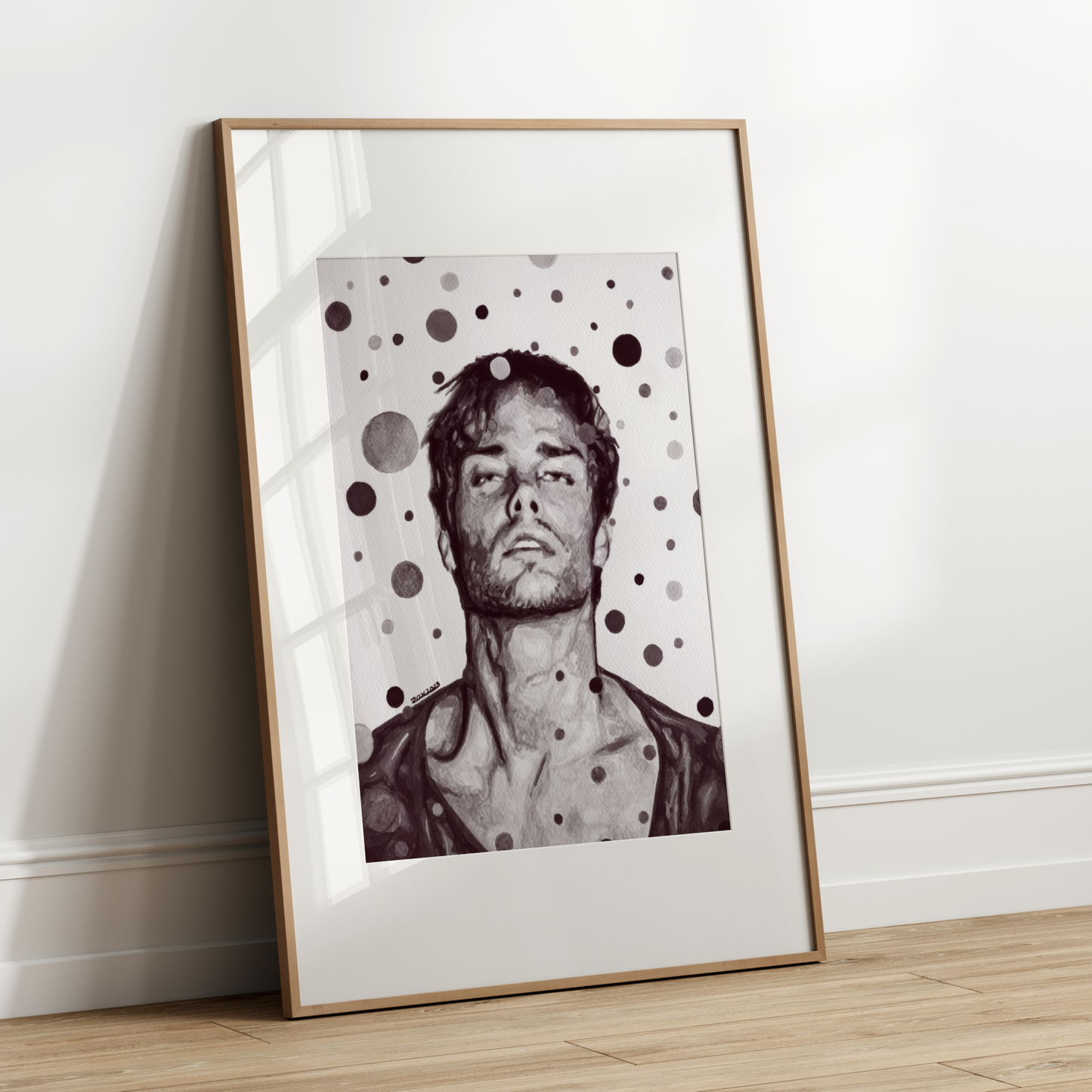 Framed artwork of a person with polka dot pattern leaning against a white wall.