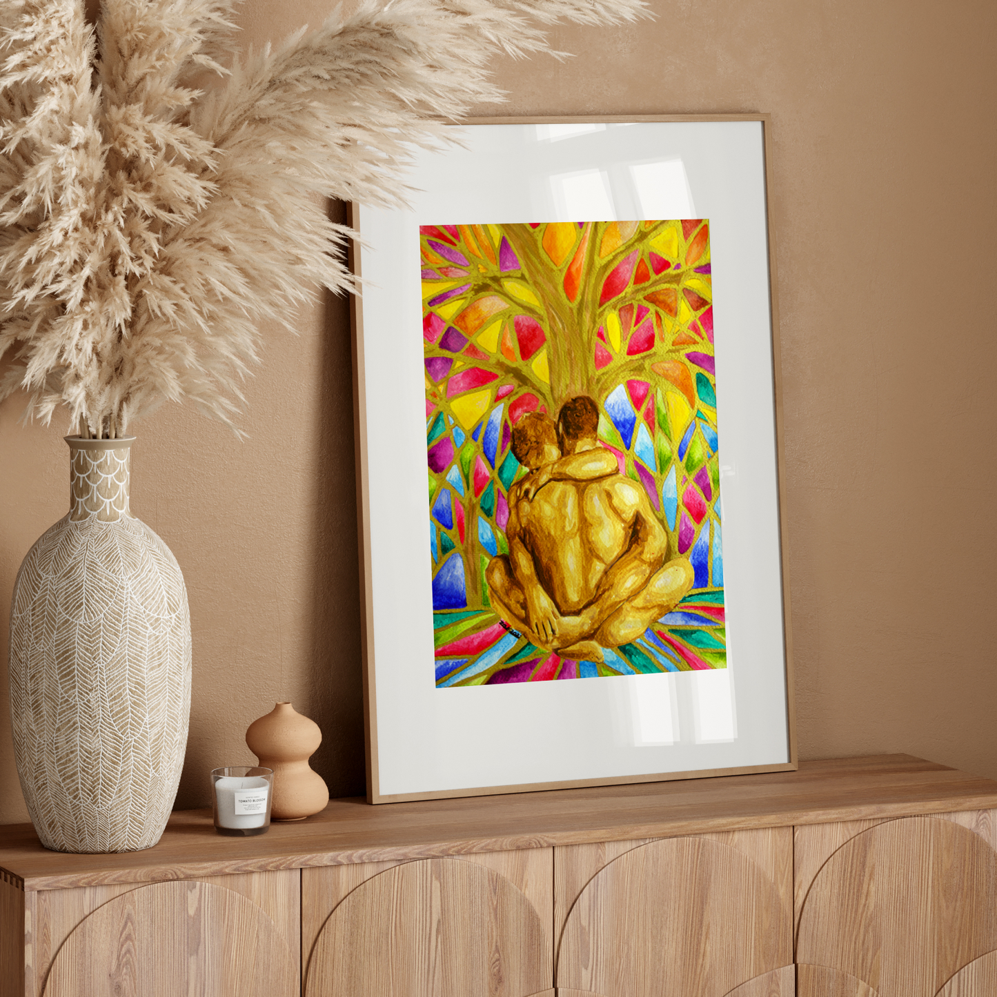 Framed colorful artwork of two people embracing on a wooden sideboard with decorative elements.