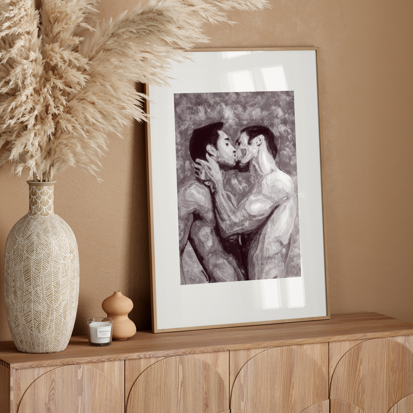 Framed artwork of two people kissing on a wooden sideboard with decorative vase and plant.
