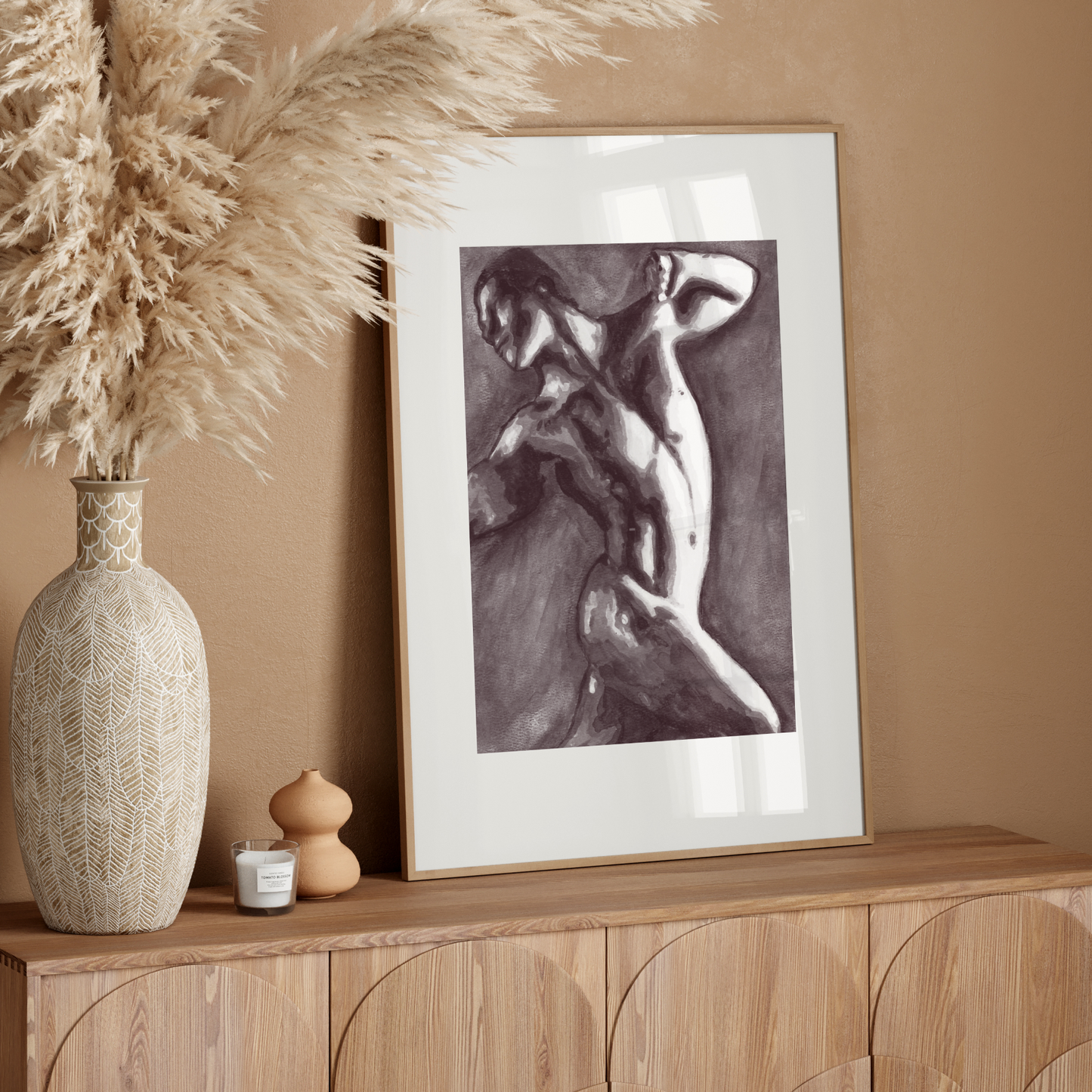 Framed artwork on a wooden console table with decorative elements against a beige wall.
