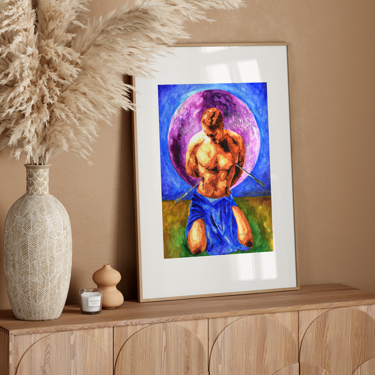 Framed artwork of a muscular figure with a colorful halo on a wooden sideboard against a beige wall.