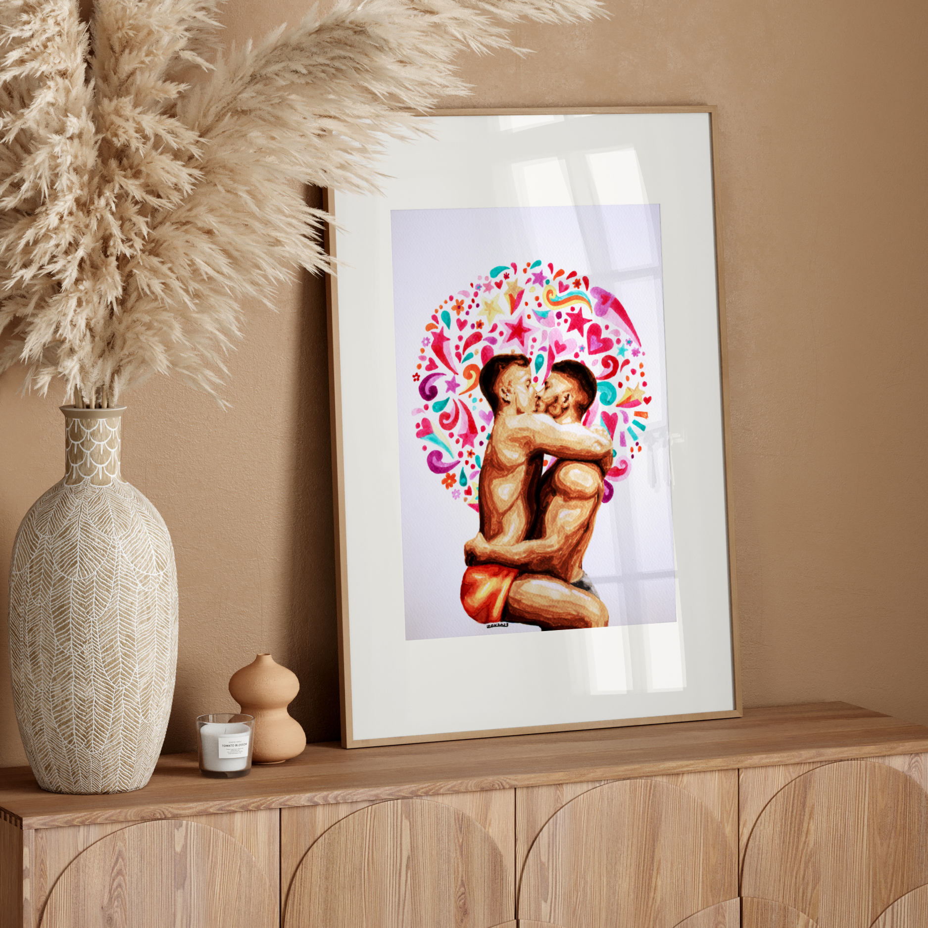 Framed artwork of two people embracing with a colorful design on a wooden sideboard against a beige wall.