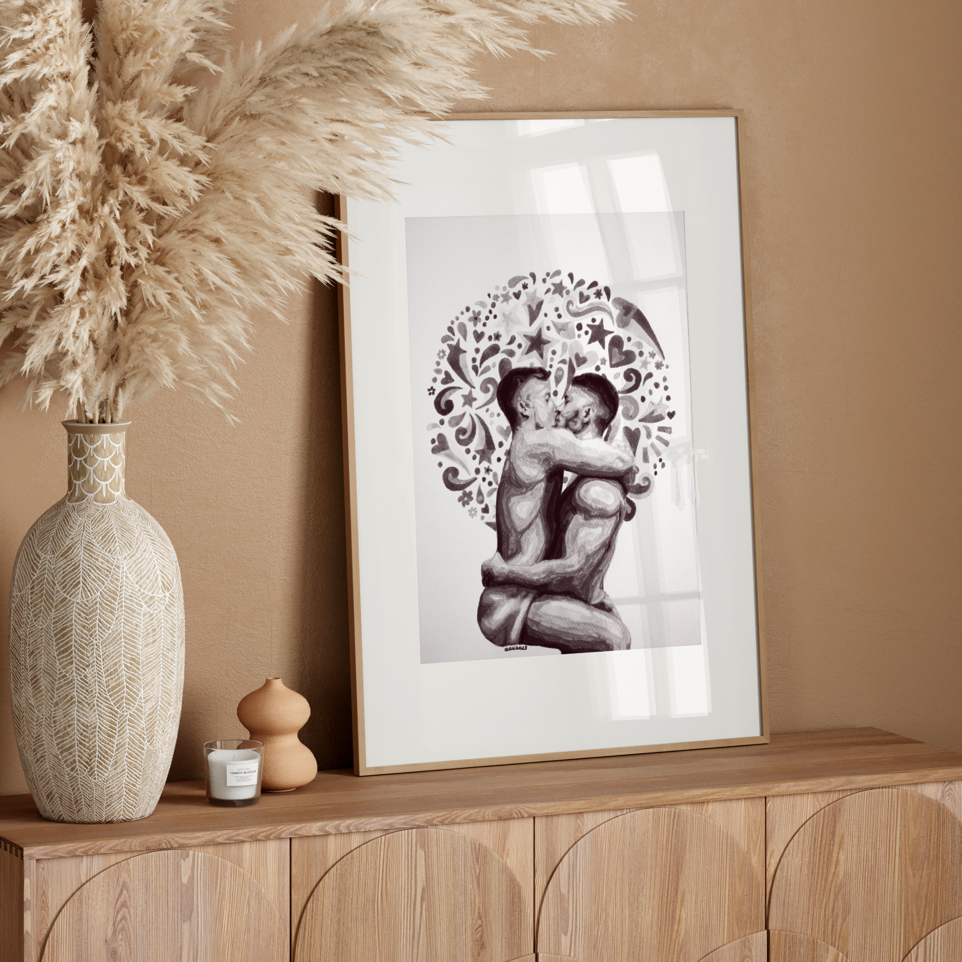 Framed artwork of a couple embracing with decorative elements on a wooden surface.