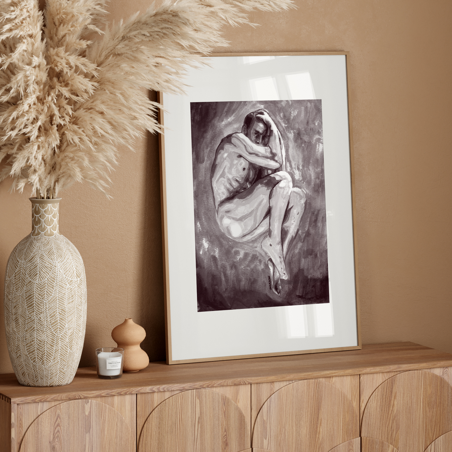 Framed artwork on a wooden console table with decorative elements against a beige wall.