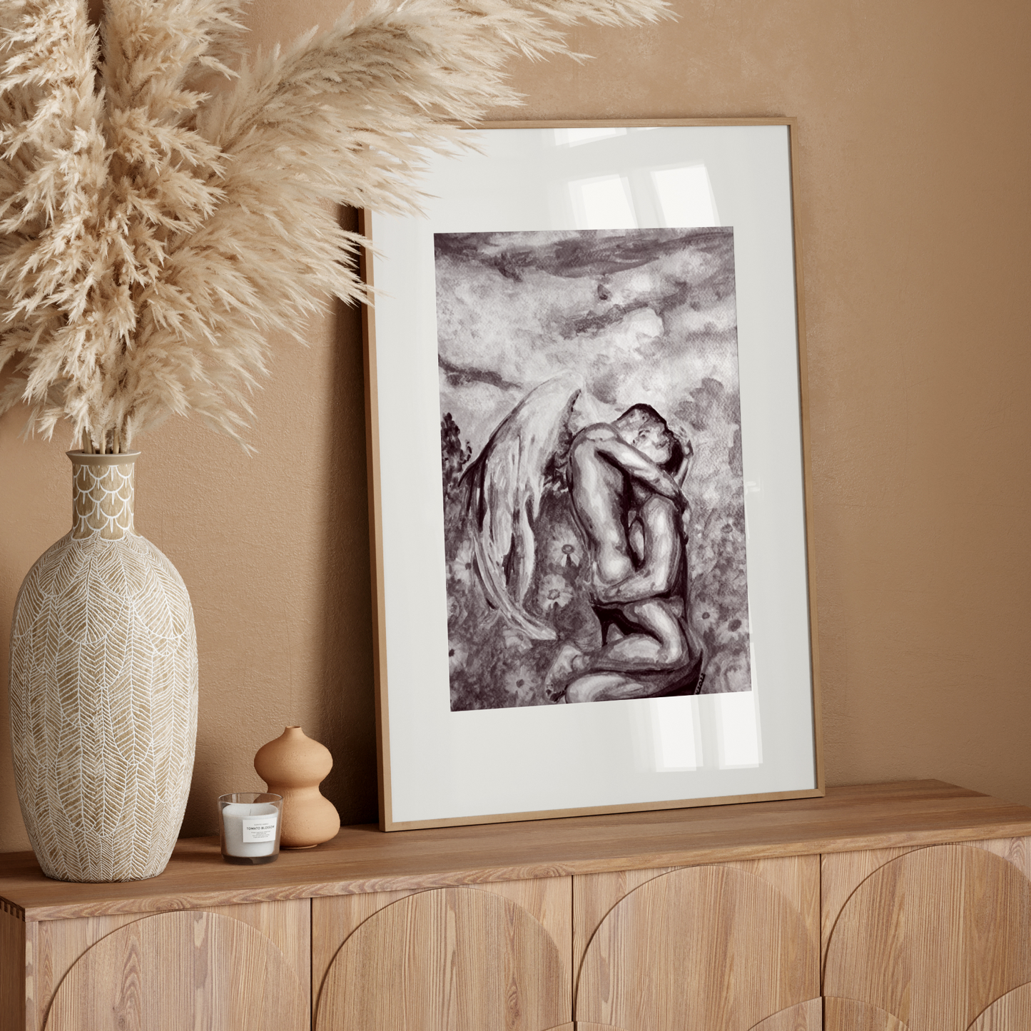 Framed artwork on a wooden console table with decorative elements against a beige wall.