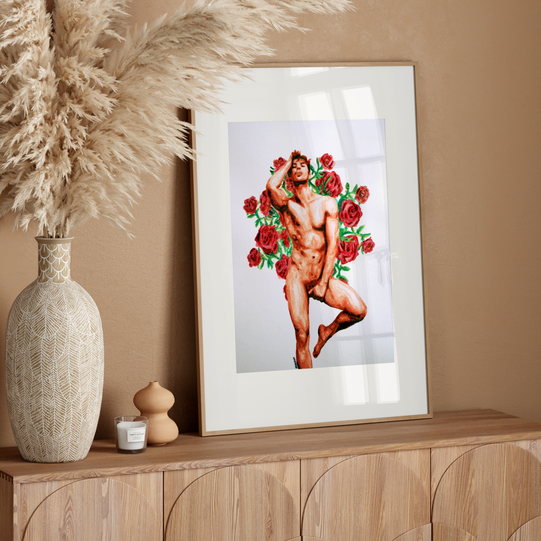 Framed artwork of a nude figure with flowers on a wooden sideboard against a beige wall.
